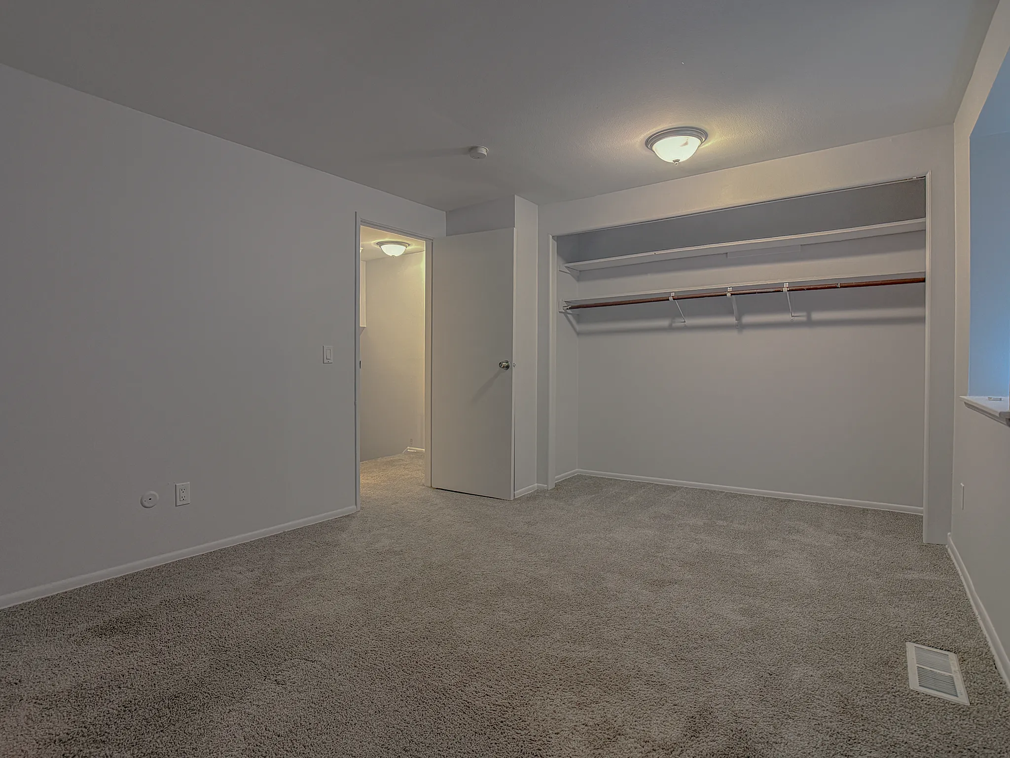 Inviting bedroom space with plush carpeting and a spacious walk-in closet, perfect for stylish storage solutions.