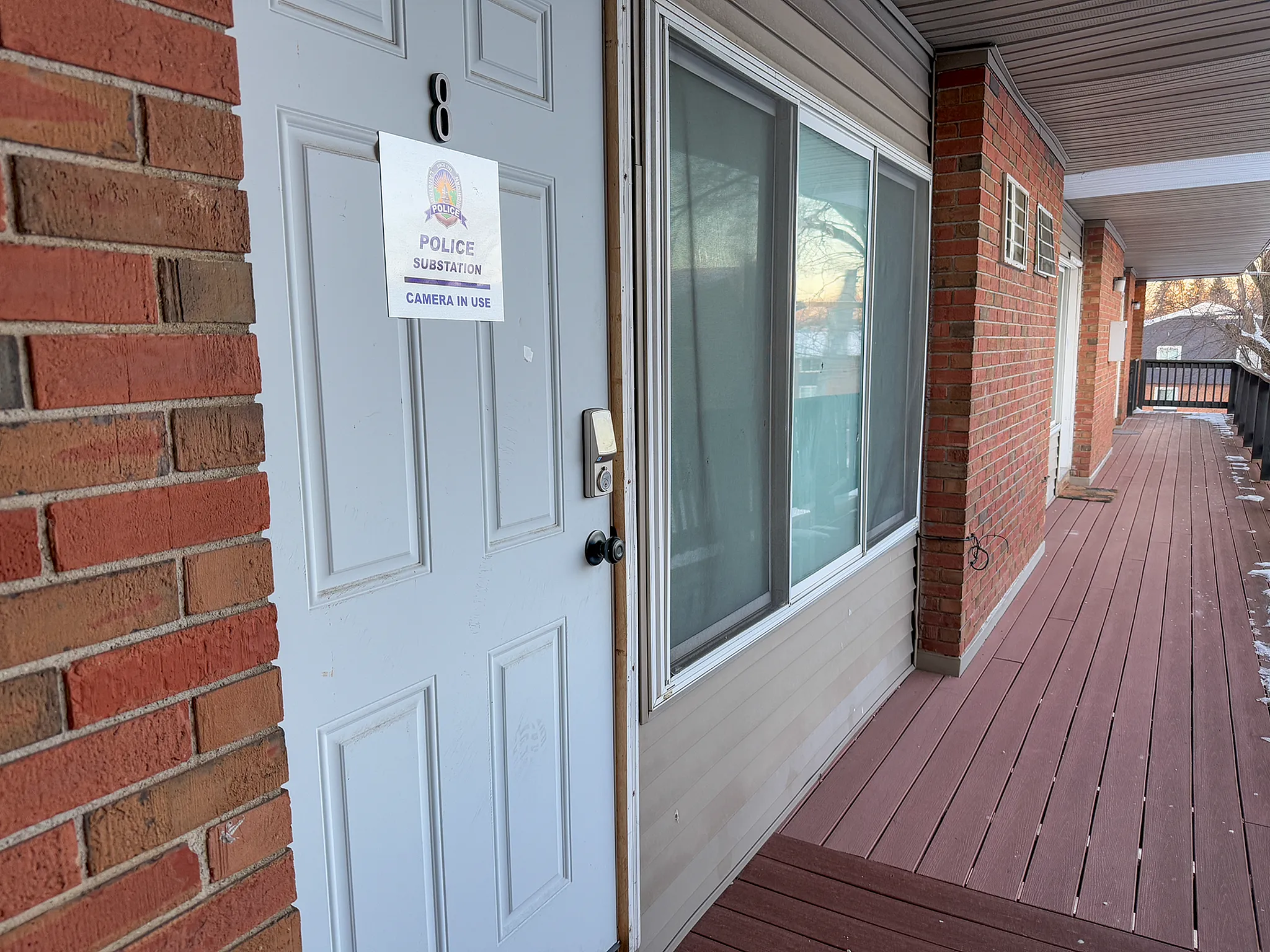 Inviting apartment entrance with smart lock, large window, and private balcony offering a charming street view.