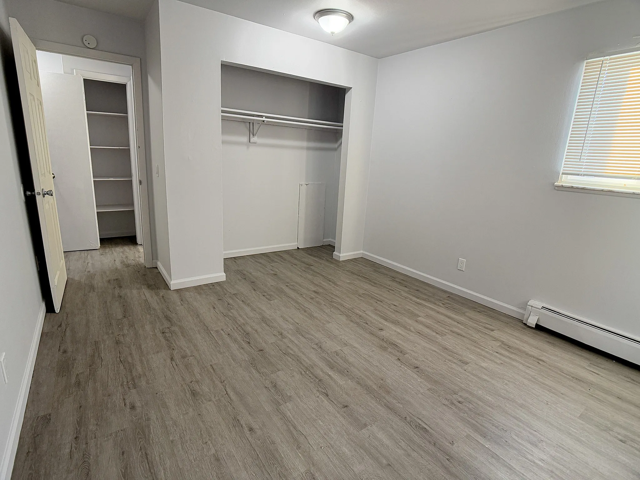 Bright and spacious bedroom with sleek, wooden flooring and ample closet space, perfect for modern living.