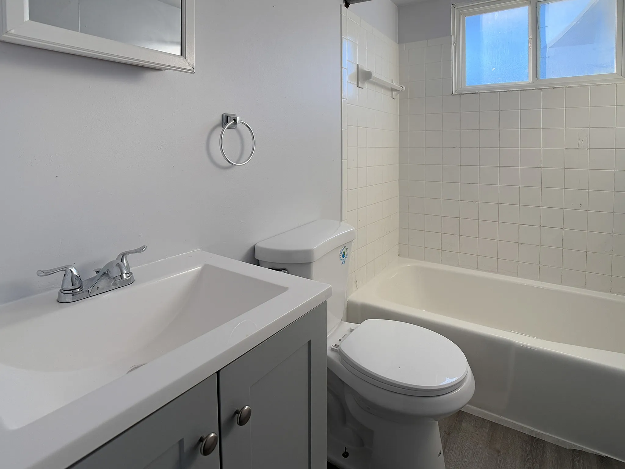 Modern bathroom featuring a sleek white vanity, polished chrome fixtures, and a clean tile backsplash with natural light streaming in.