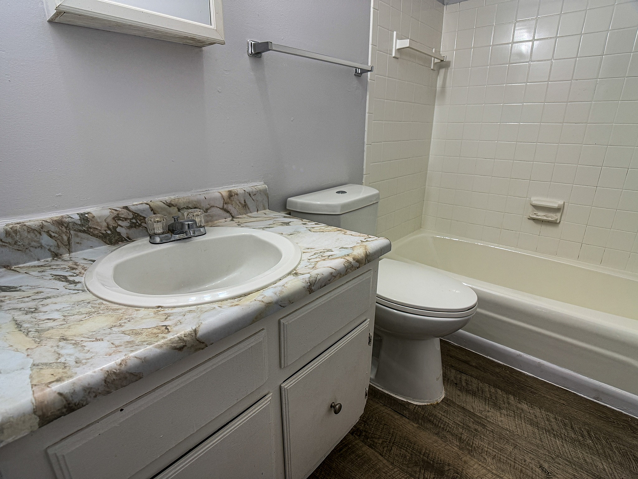 Charming bathroom with elegant marble countertop and a classic white bathtub, offering style and comfort.