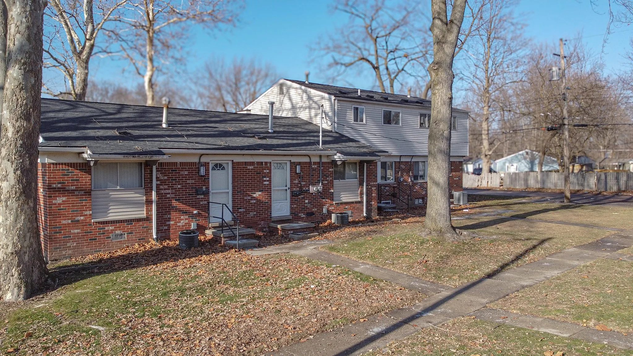 Charming brick townhouse with inviting front entrances, large trees, and a peaceful neighborhood setting.