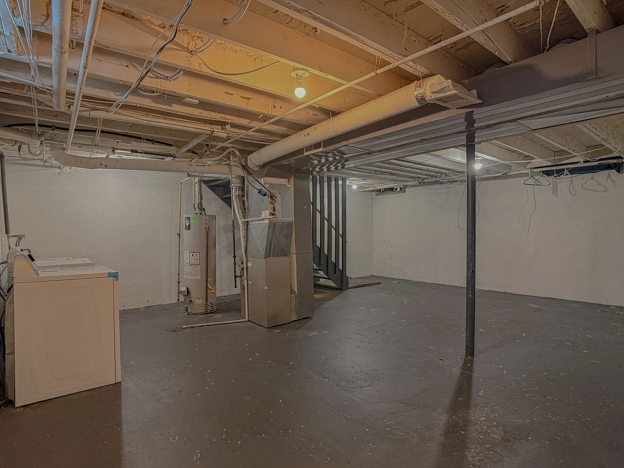 Spacious basement area boasting high ceilings, an efficient water heater, and convenient laundry facilities.