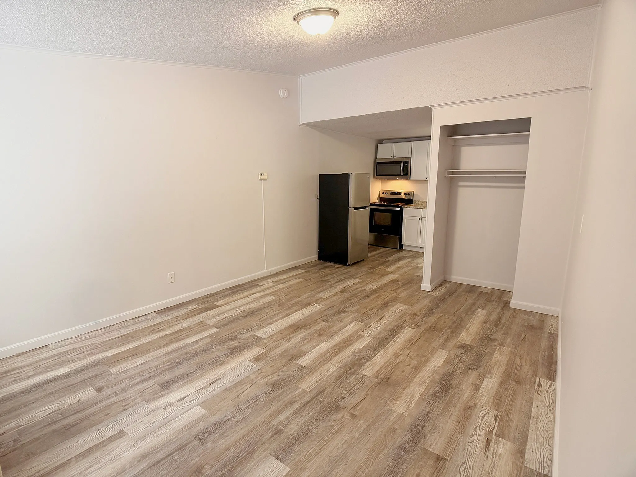 Inviting modern apartment with sleek hardwood flooring, featuring a stylish kitchen equipped with stainless steel appliances and an ample open space.