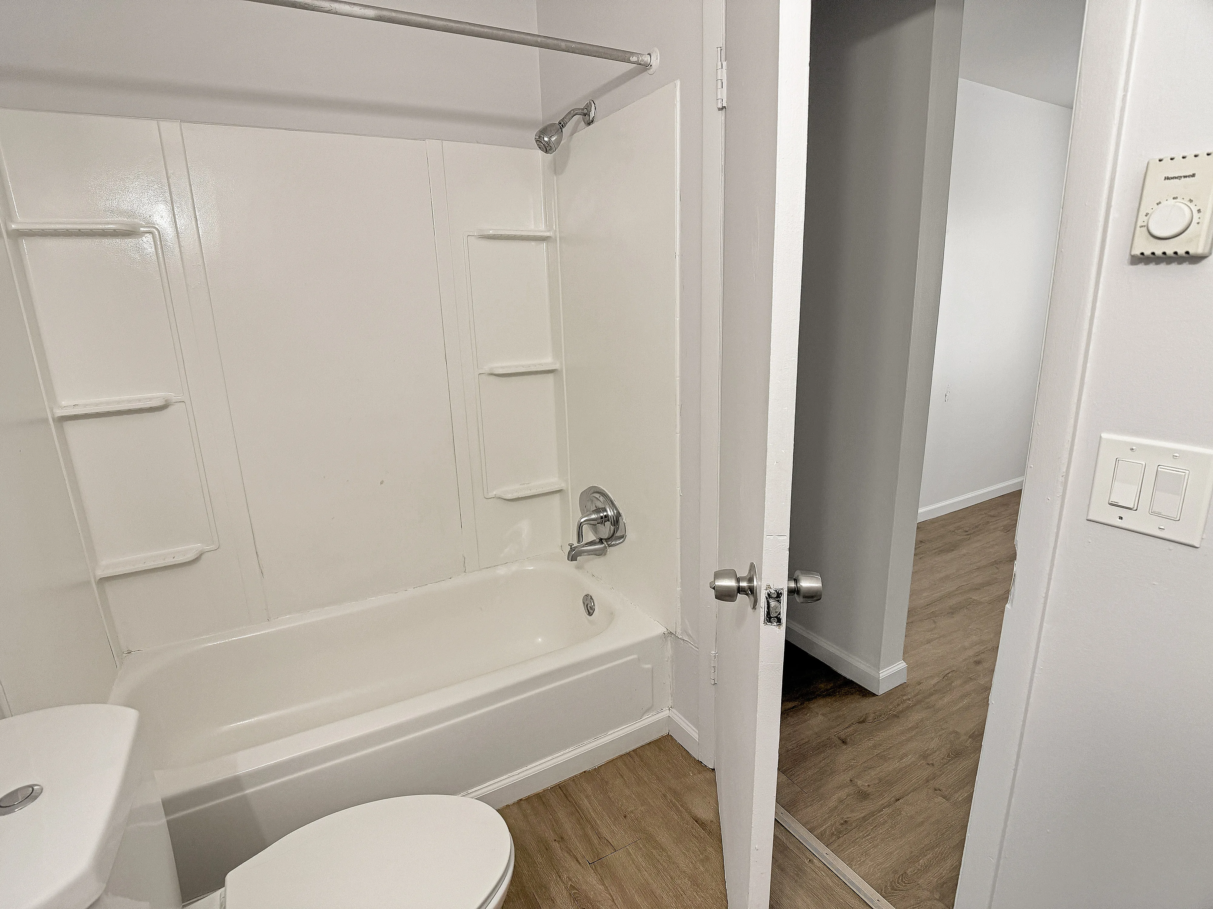 Modern bathroom with white bathtub, sleek fixtures, and elegant wood flooring, showcasing a contemporary apartment design.