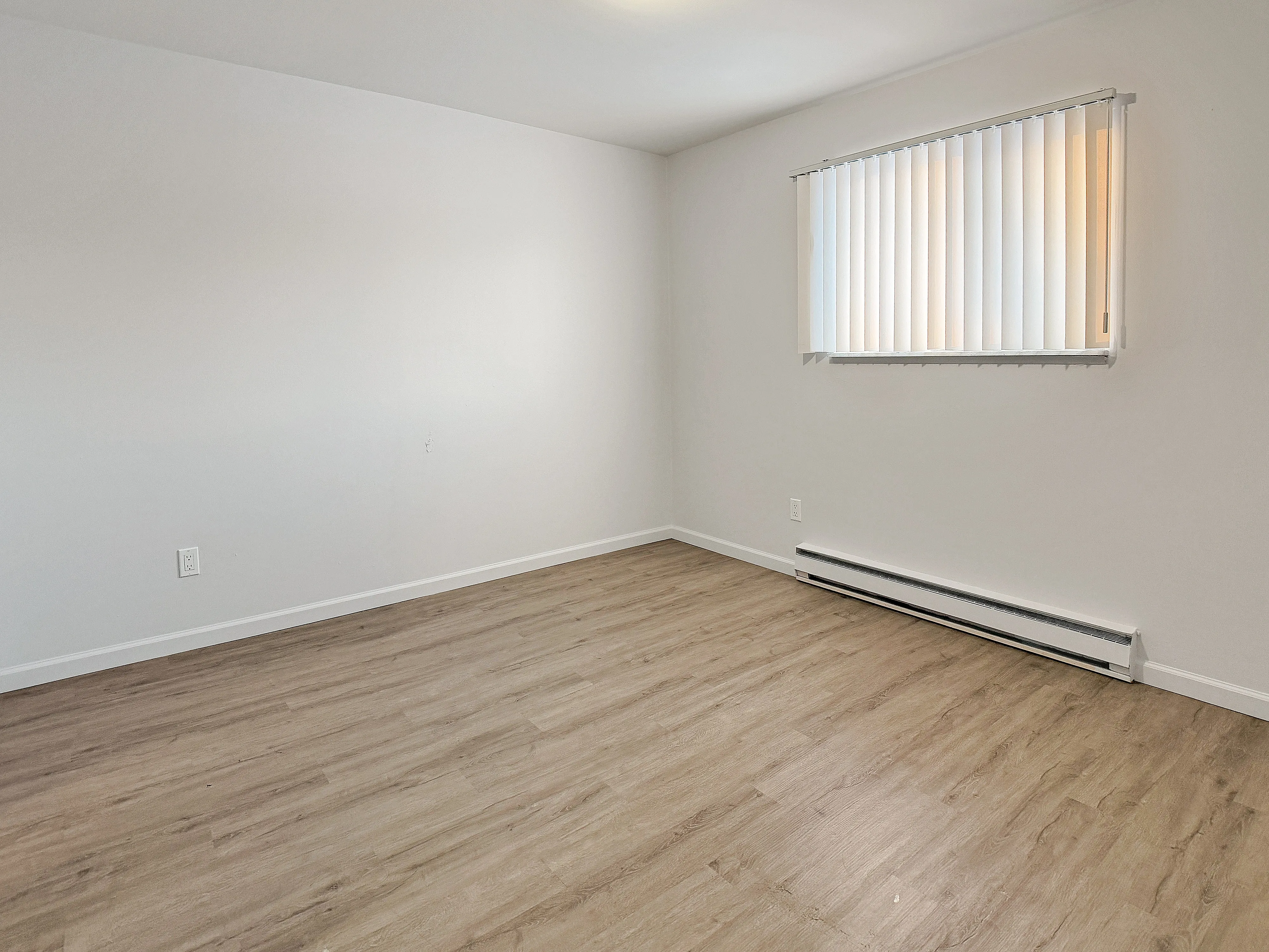 Bright and airy room with modern laminate flooring and a large window offering ample natural light.