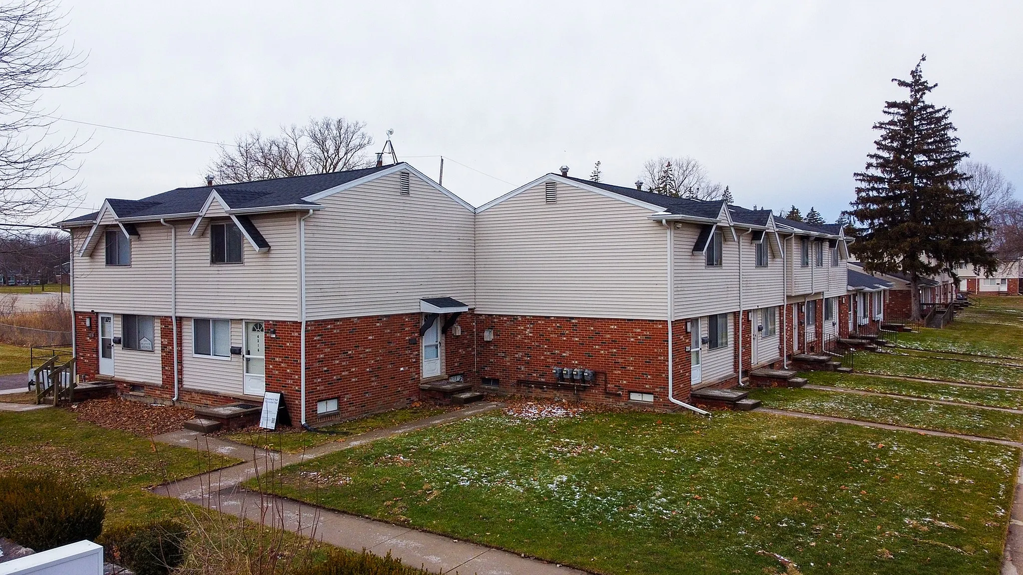 Charming row of townhouses with brick and siding exterior, inviting pathways, and quaint neighborhood setting.