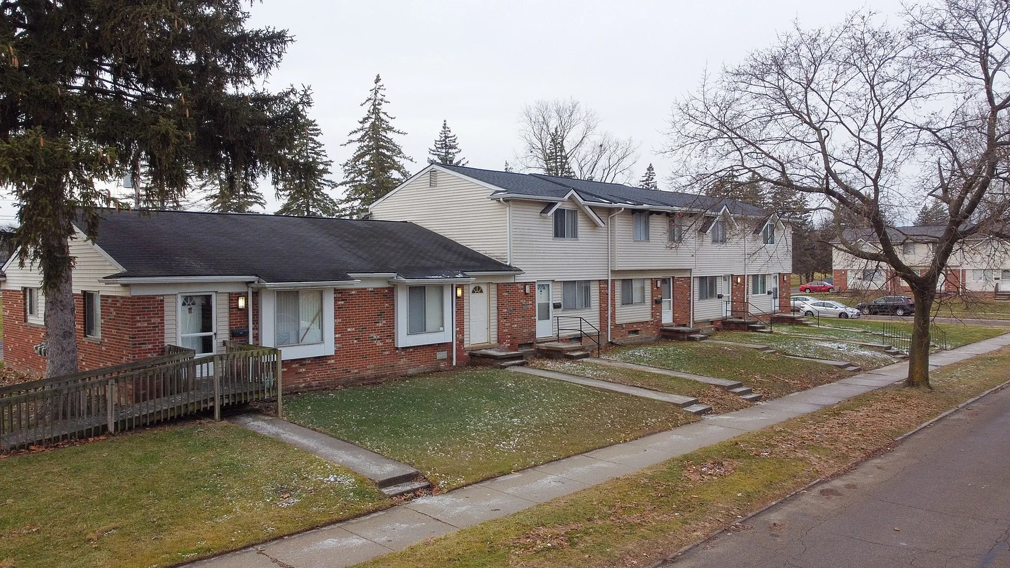 Charming picture of townhouses with brick and siding exterior, nestled in a tranquil neighborhood with mature trees and manicured lawns.