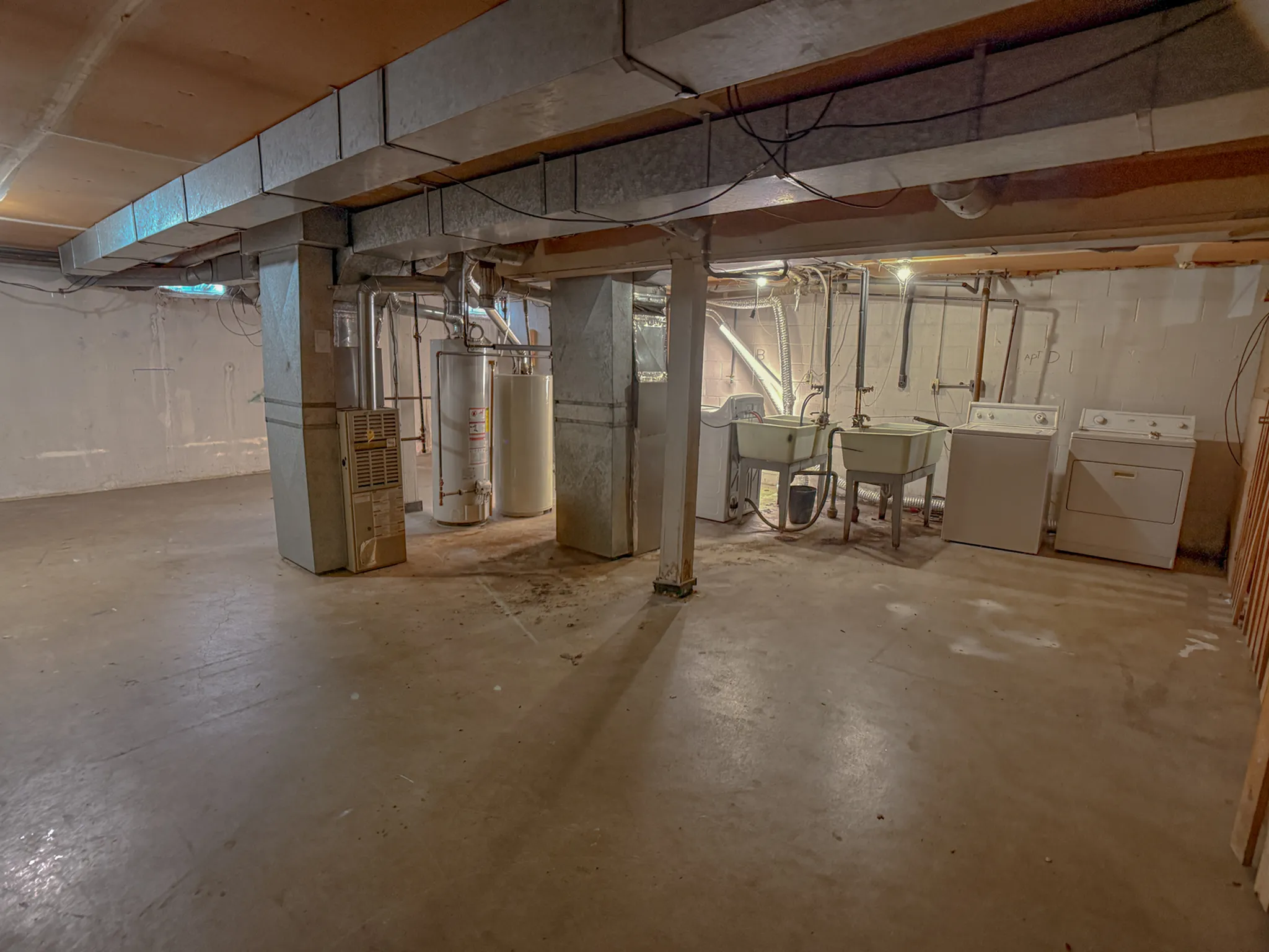 Spacious basement with washer, dryer, utility sinks, and ample storage potential, ideal for a functional home setup.