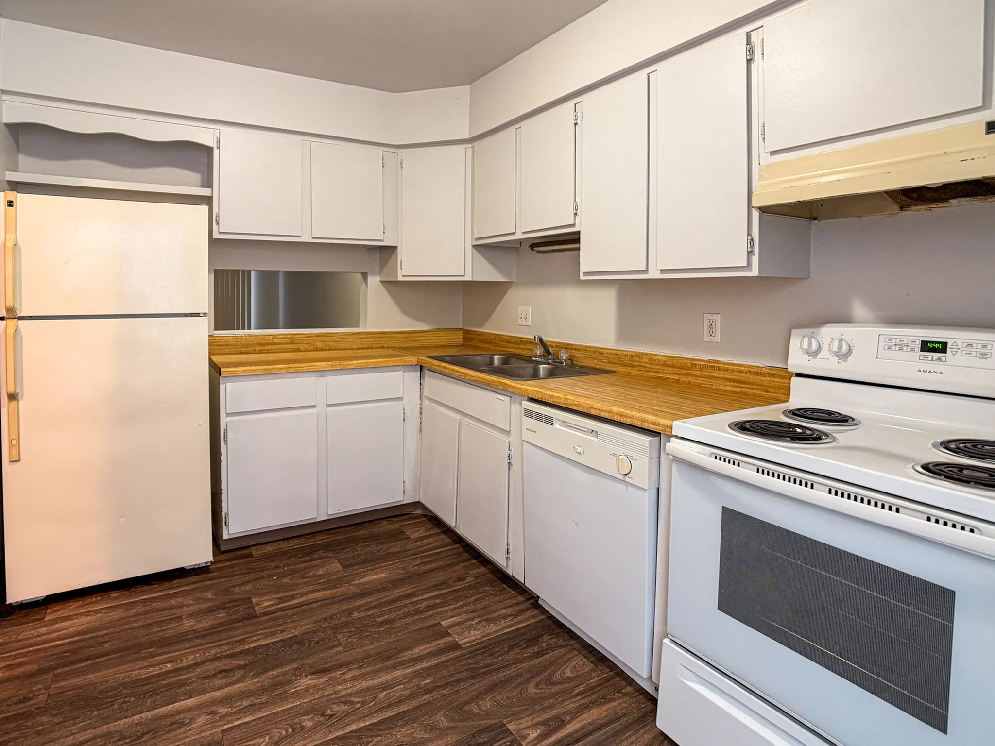 Charming kitchen with modern wooden flooring, ample cabinetry, and sleek appliances for a functional cooking space.