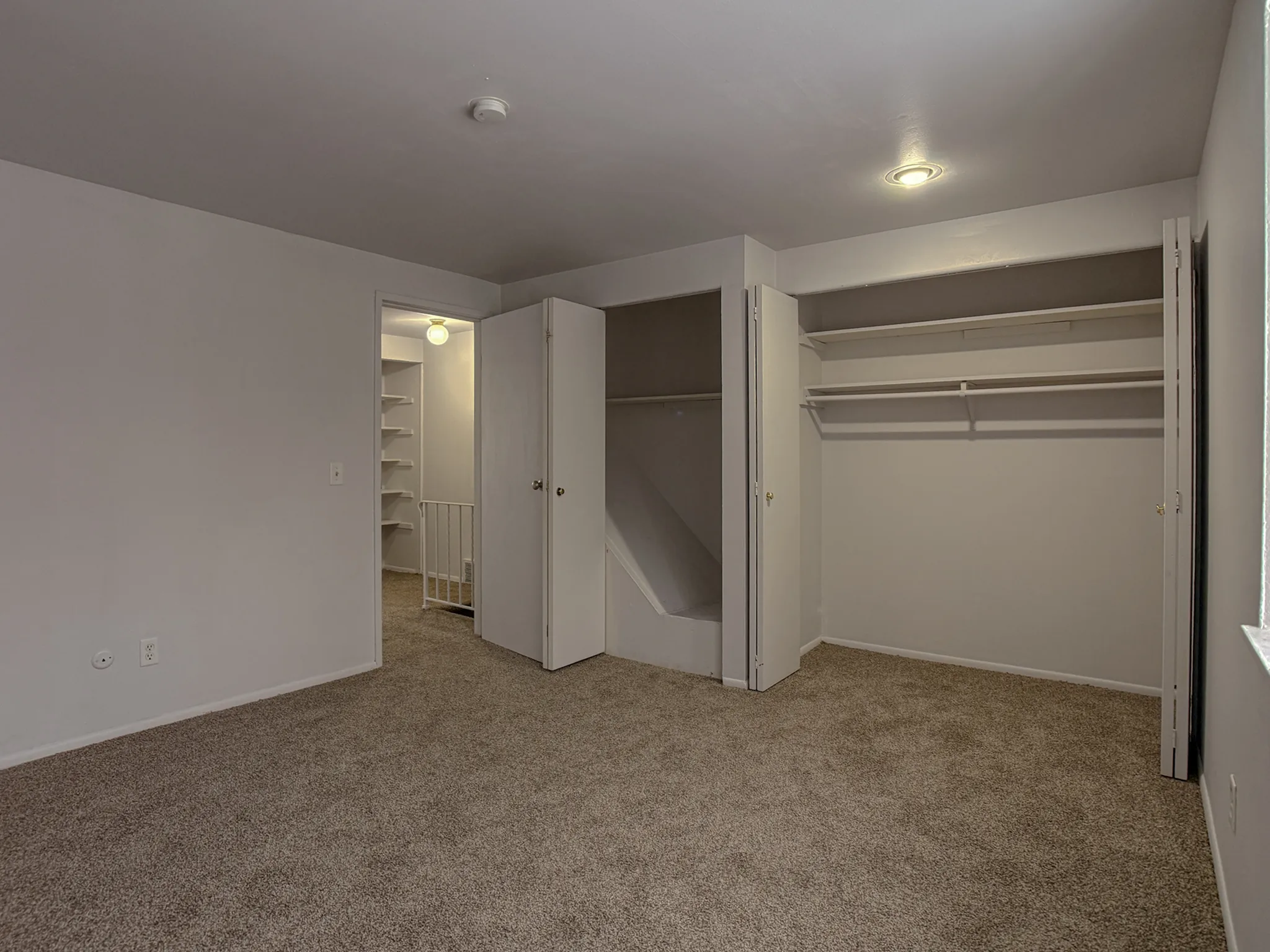 Cozy bedroom featuring plush carpeting, spacious built-in closets, and natural lighting.