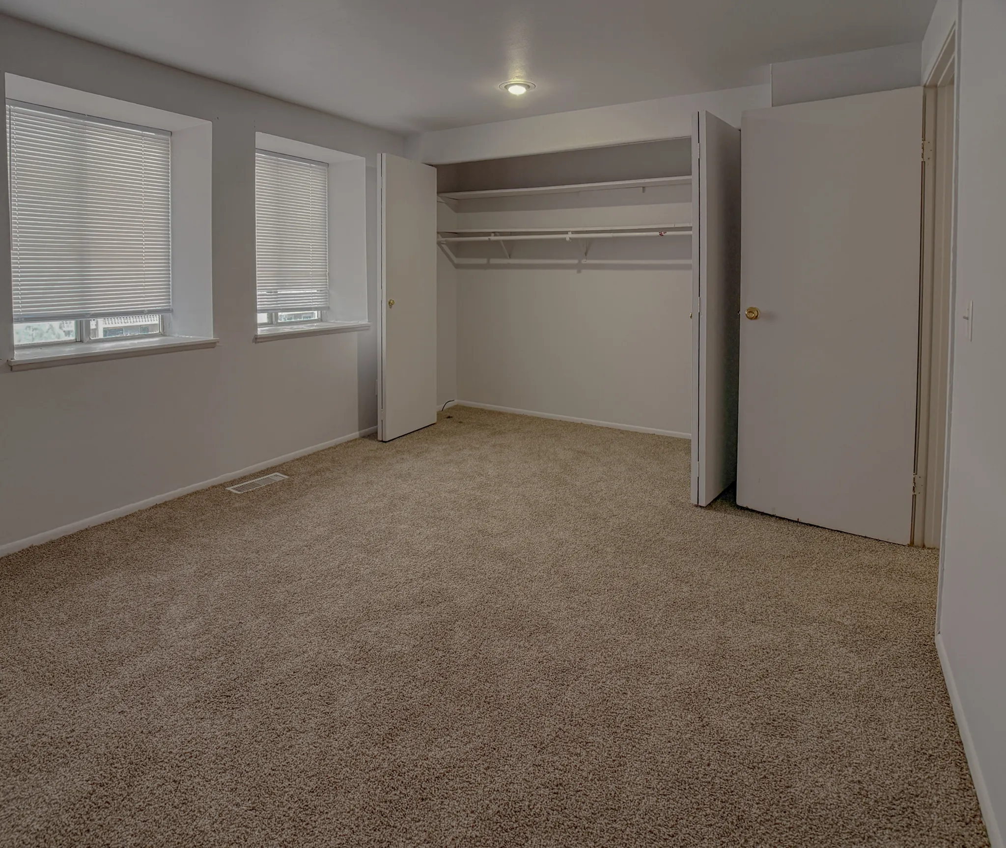 Spacious, bright bedroom with plush carpet, large windows, and ample closet space.