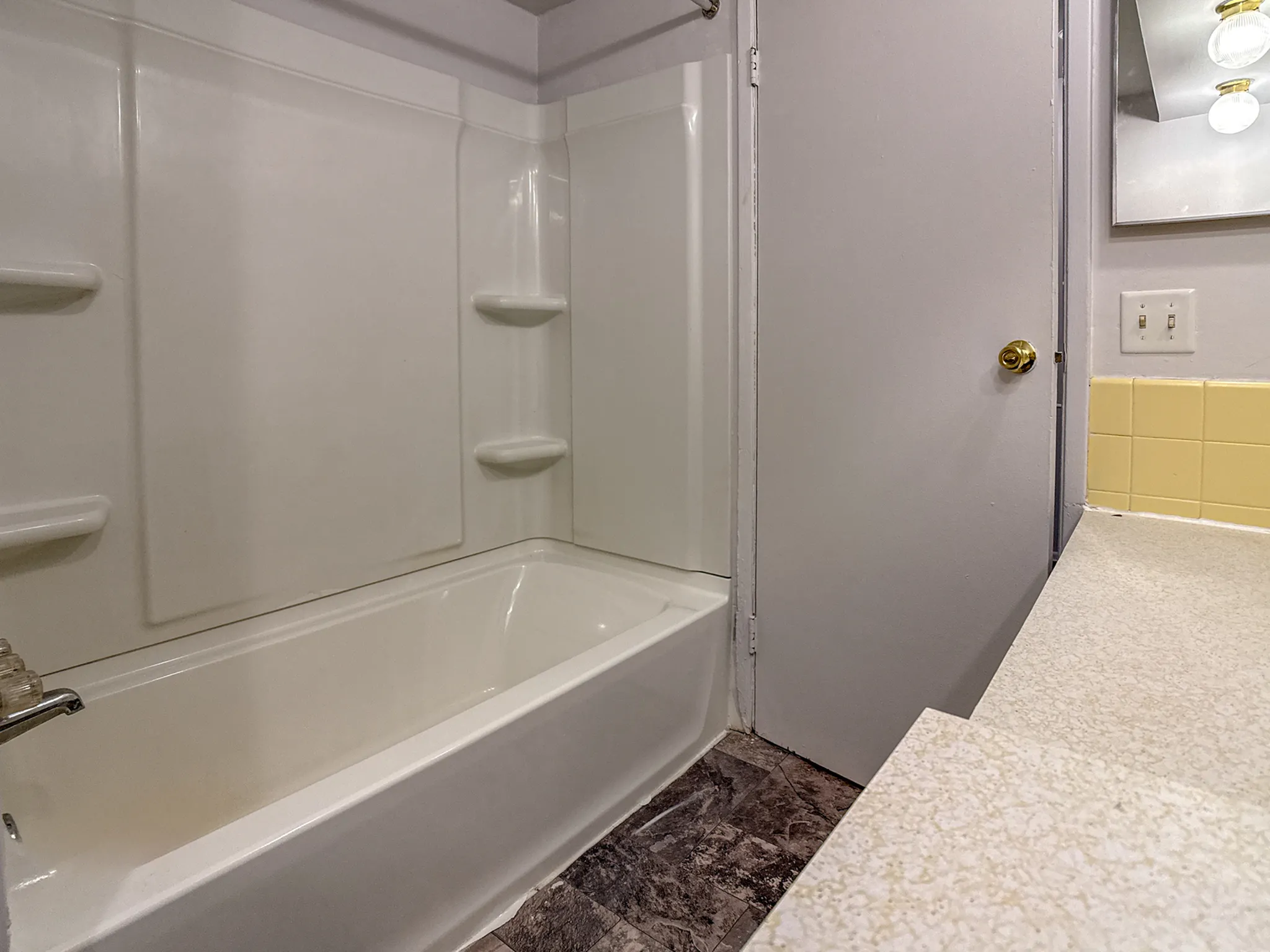 Charming bathroom featuring a clean white bathtub, elegant countertop, and vintage lighting fixtures.