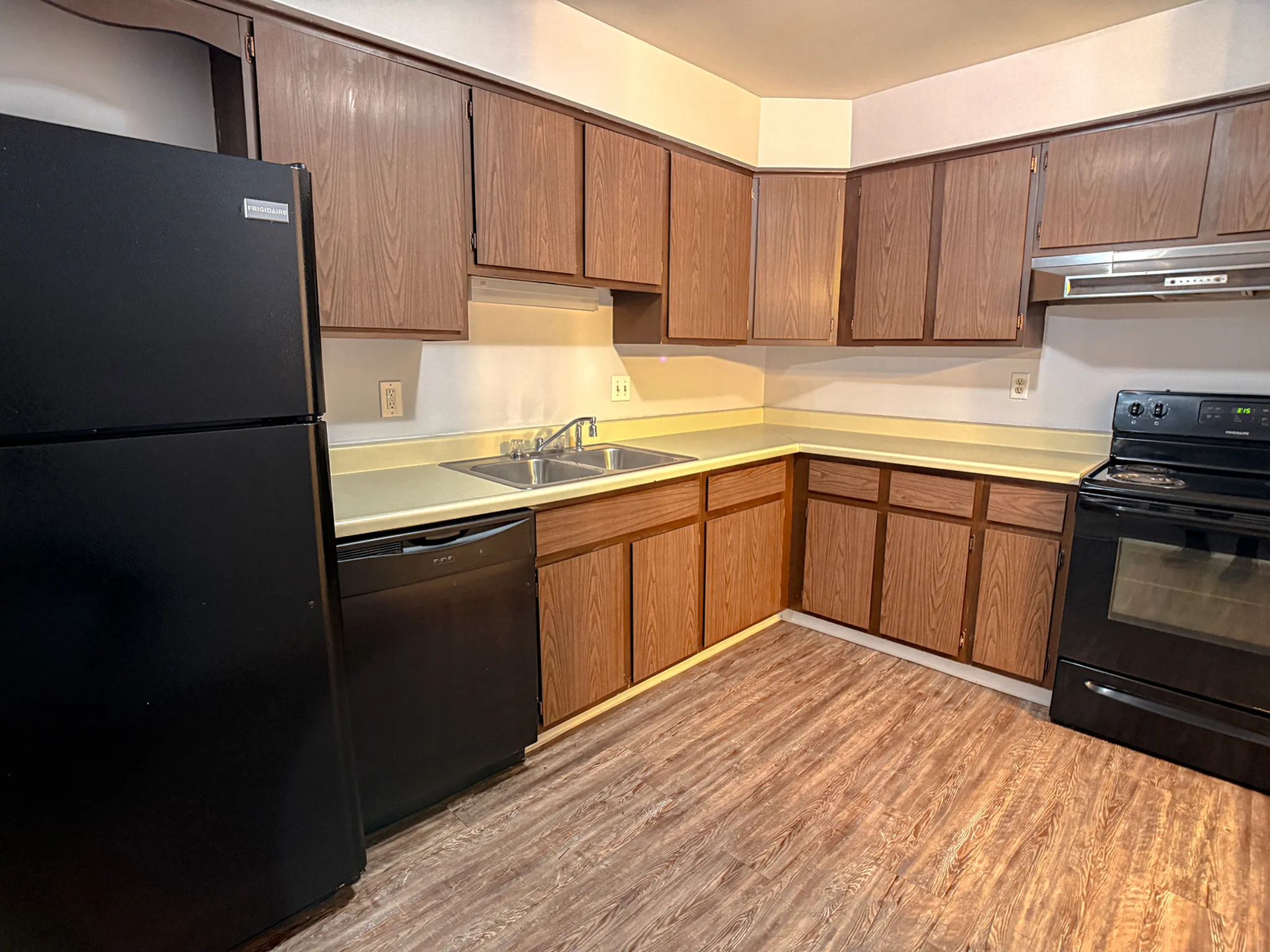 Cozy kitchen with wooden cabinetry, modern black appliances, and ample countertop space, perfect for culinary creativity.