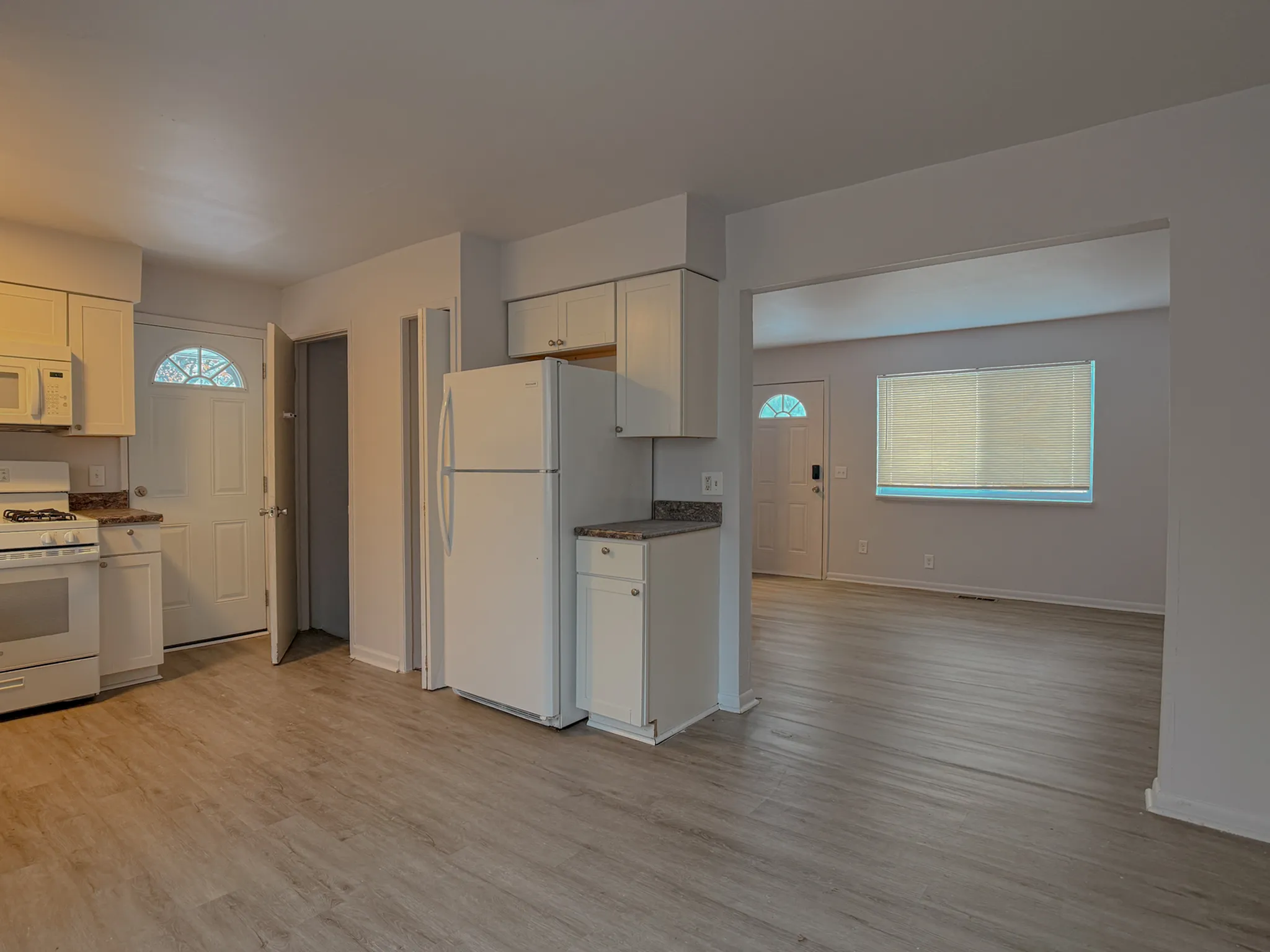 Bright and inviting open-plan kitchen and living room with modern appliances and stylish light wood flooring.