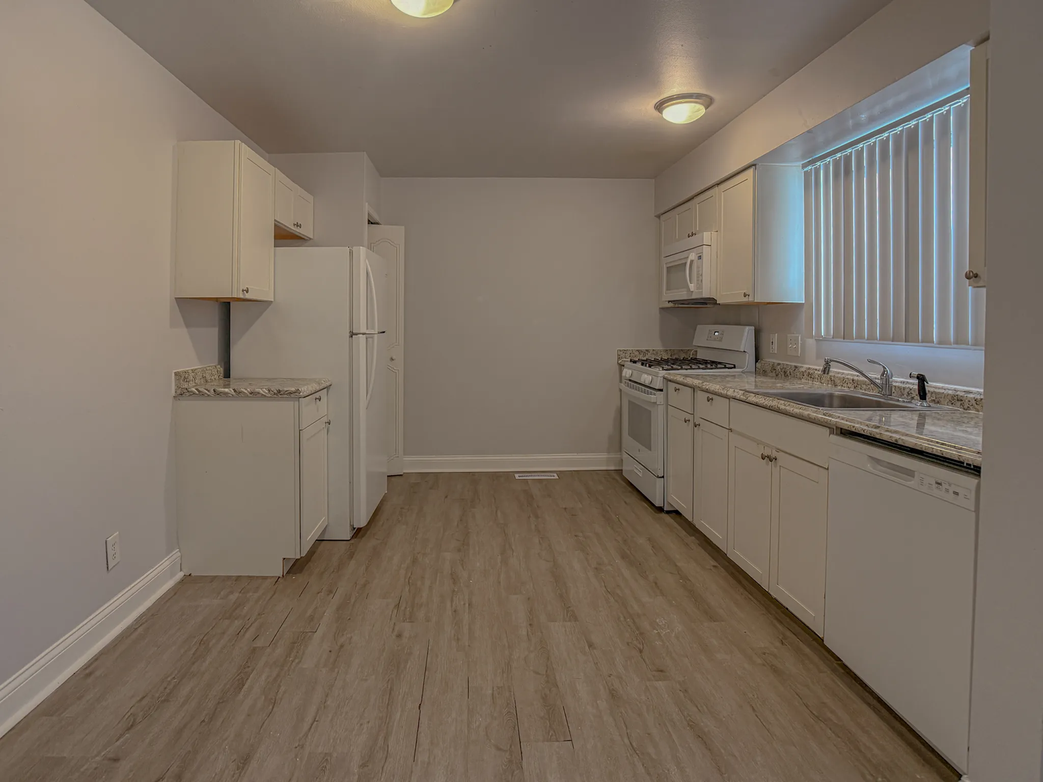 Modern kitchen with sleek cabinetry, granite countertops, and wood flooring.