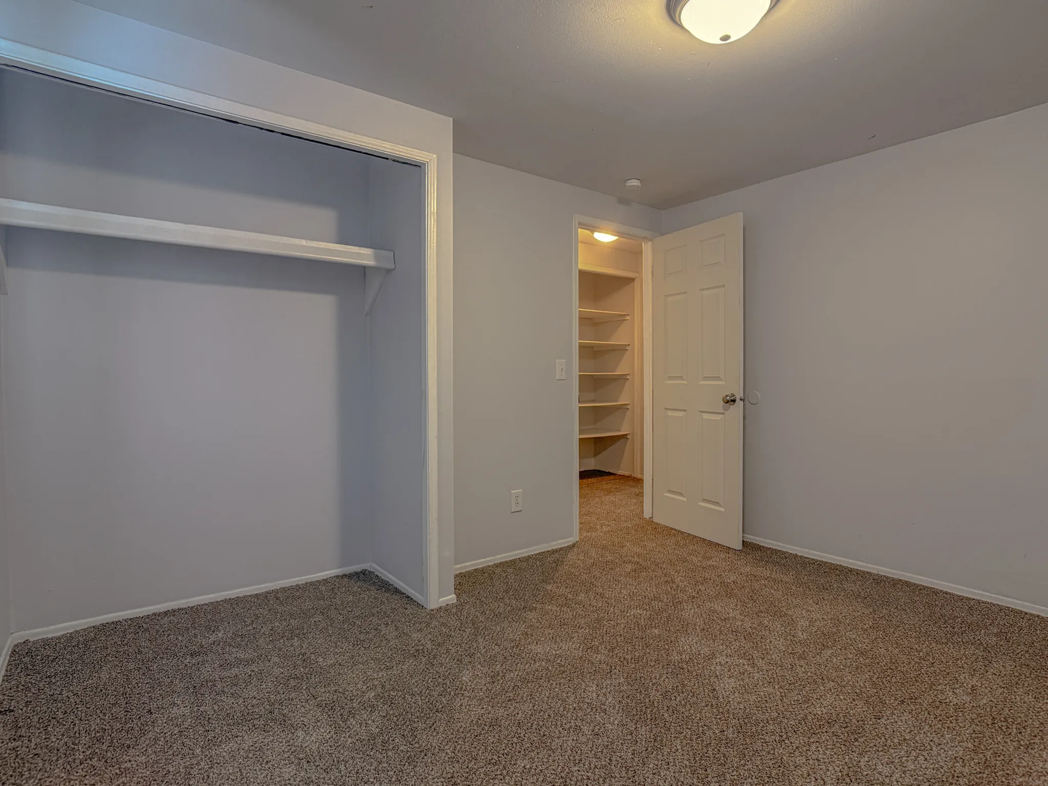 Inviting bedroom with plush carpet, spacious closet, and built-in shelving for ample storage solutions.