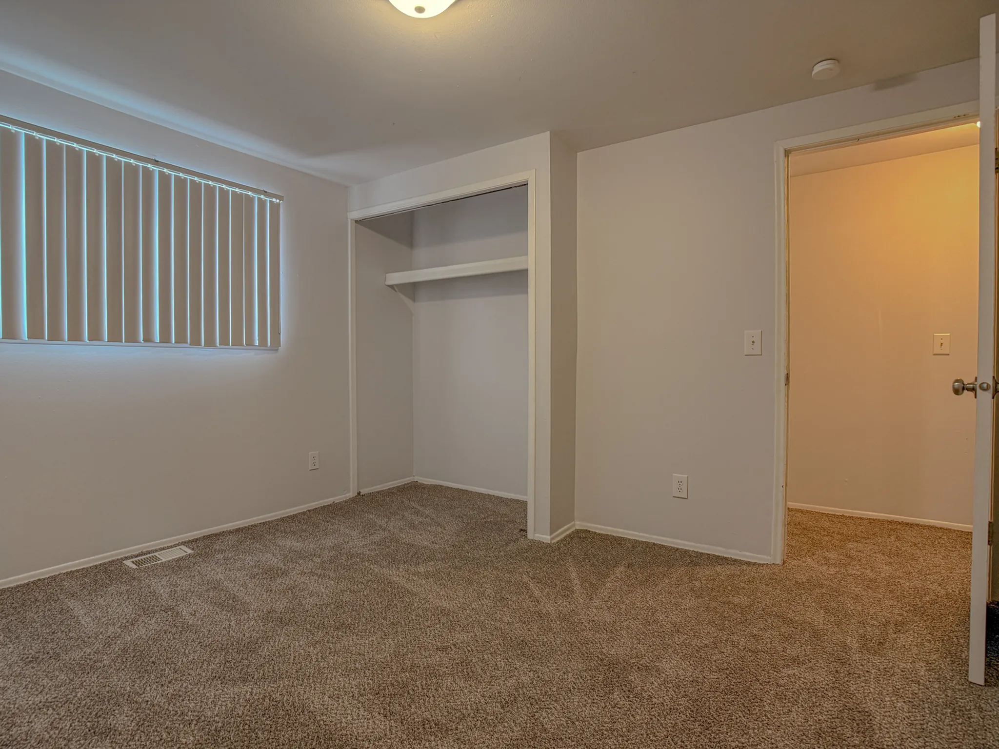 Inviting bedroom with plush carpeting, large closet space, and ample natural light from a wide window.