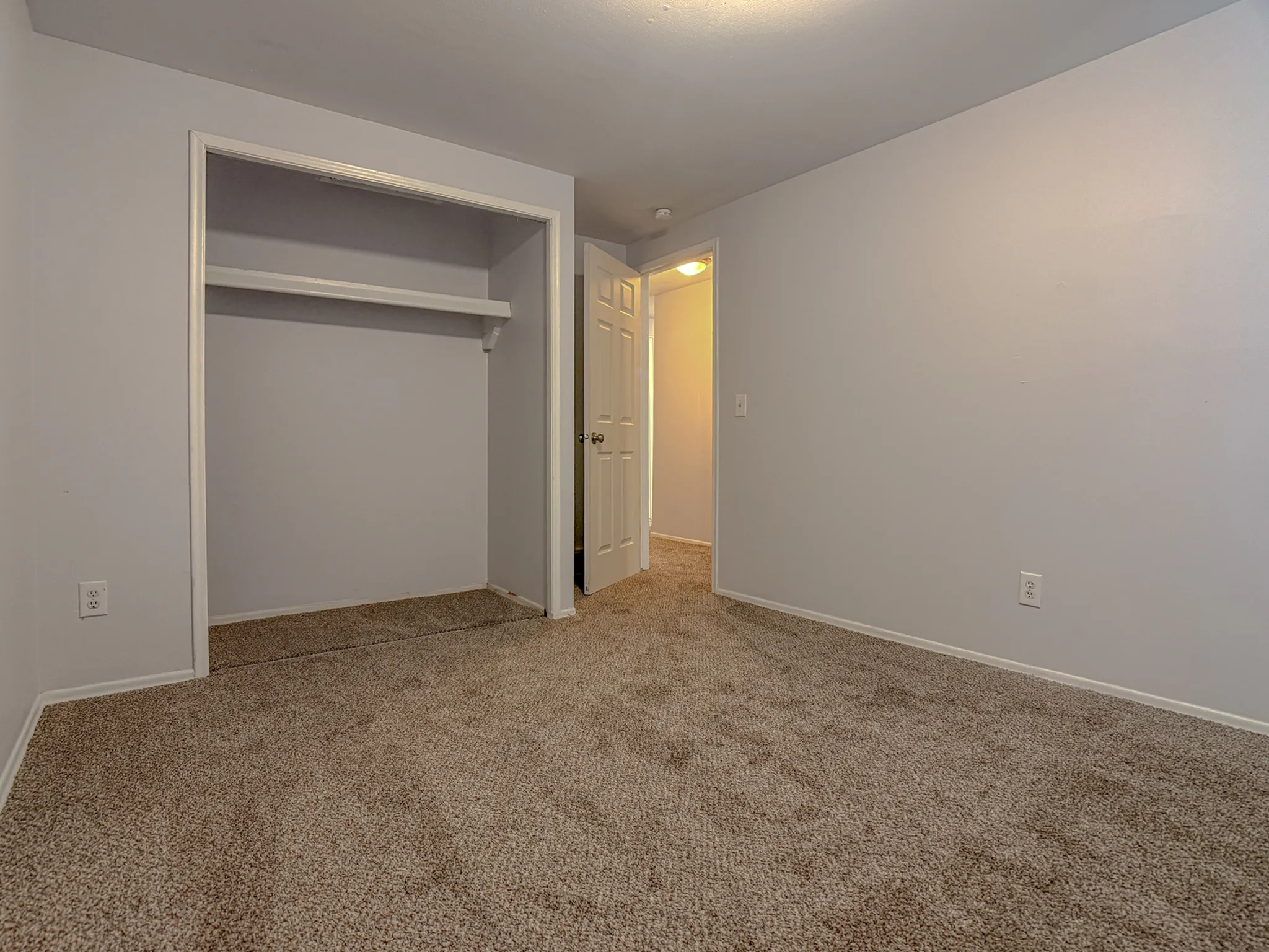 Cozy bedroom with plush carpet flooring, built-in closet, and soft lighting, creating a warm and inviting atmosphere.