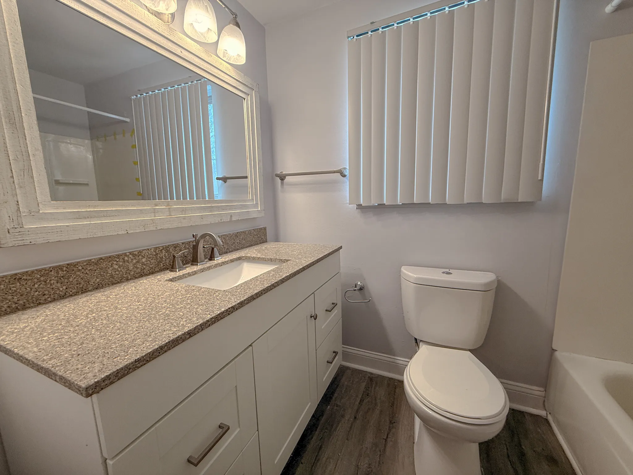 Modern bathroom with elegant vanity, granite countertop, large mirror, and sleek tile flooring.