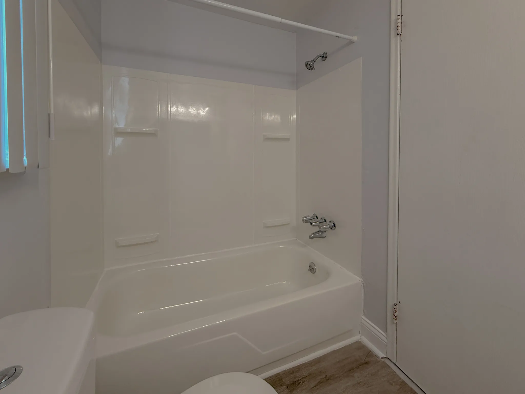 Elegant bathroom featuring a pristine bathtub with built-in shelving and modern fixtures.