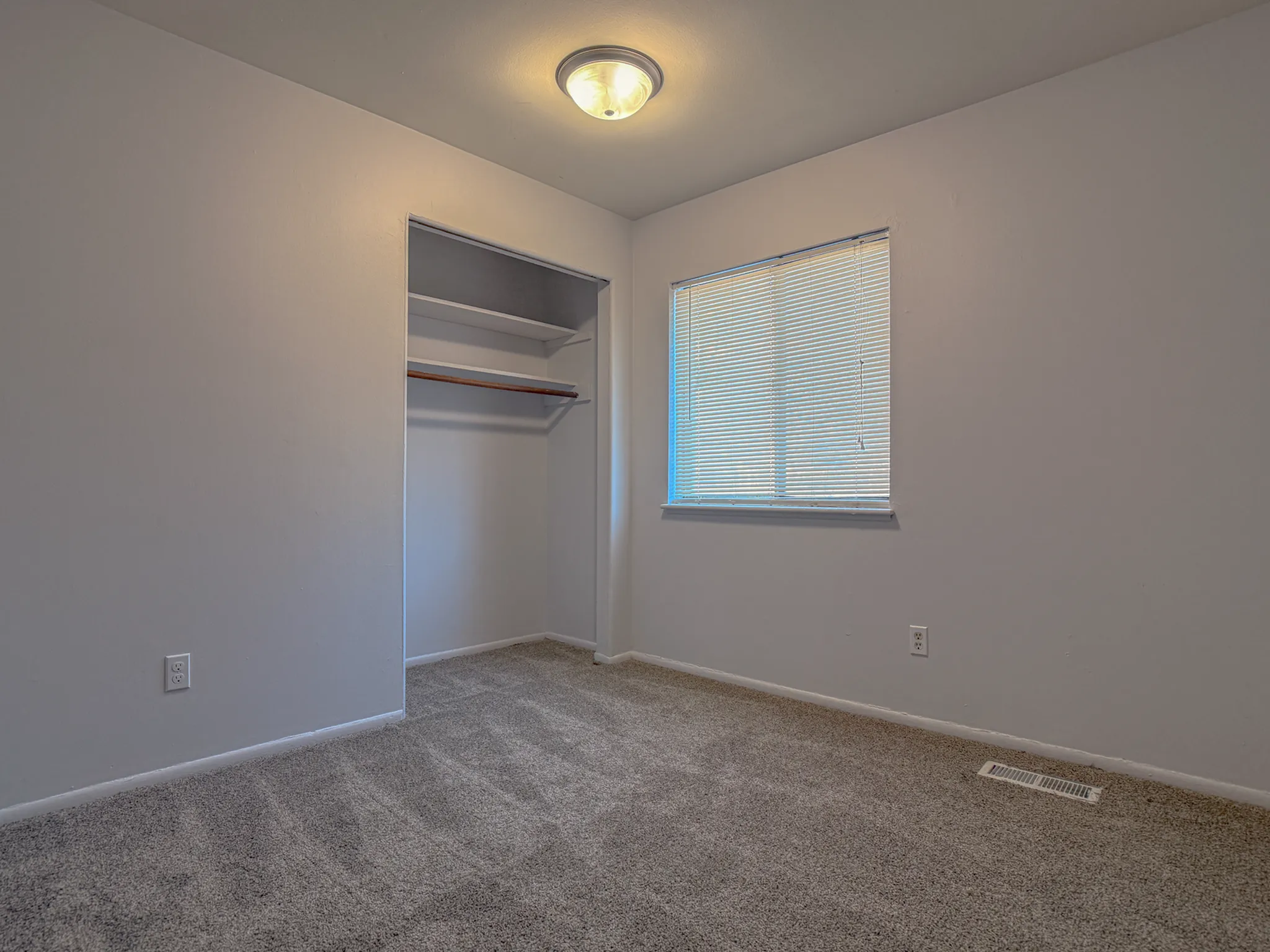 Bright and cozy bedroom with plush carpet, ample closet space, and a large window for natural light.