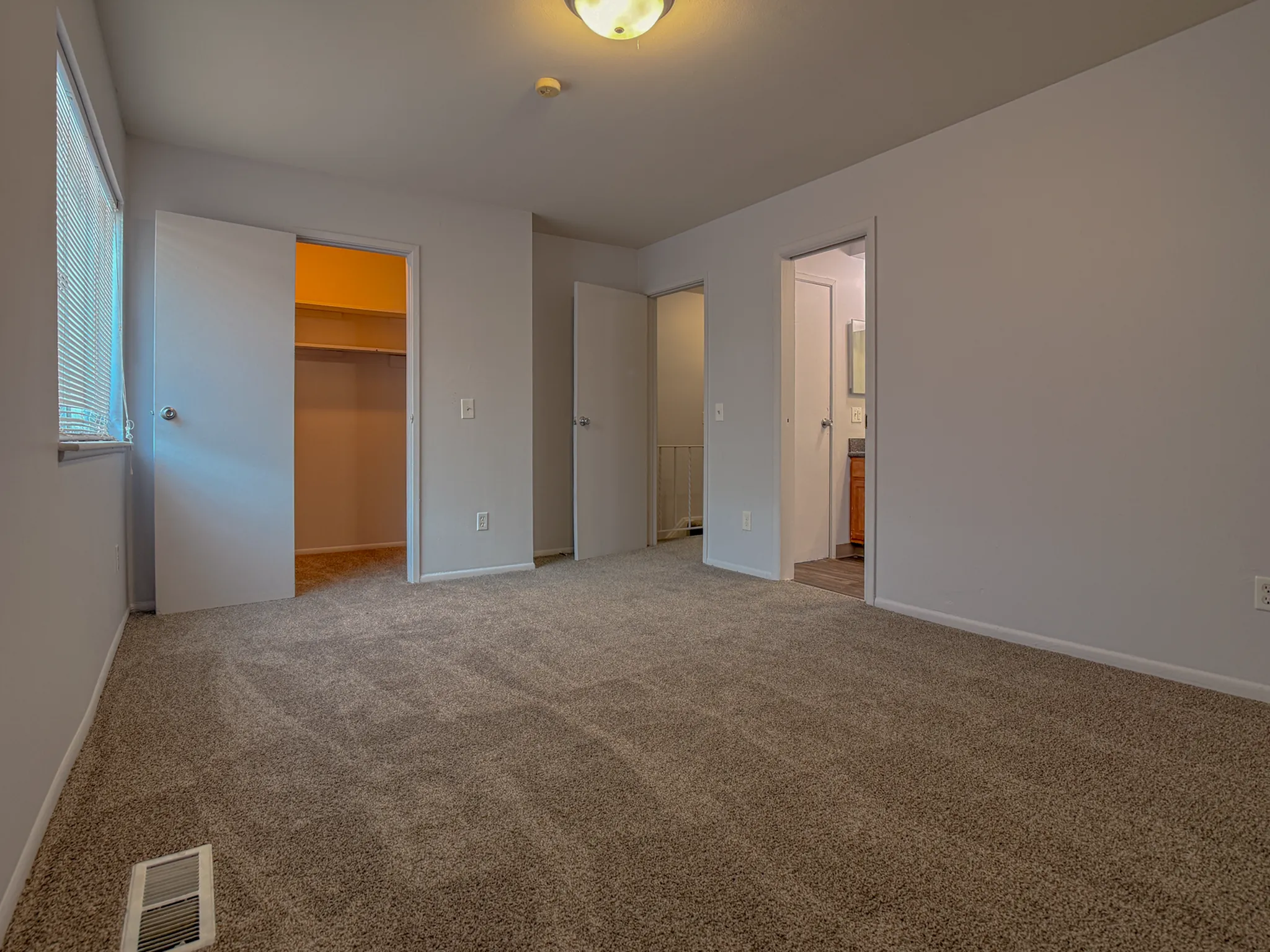 Inviting bedroom with plush carpeting, ample closet space, and soft natural light from a side window.