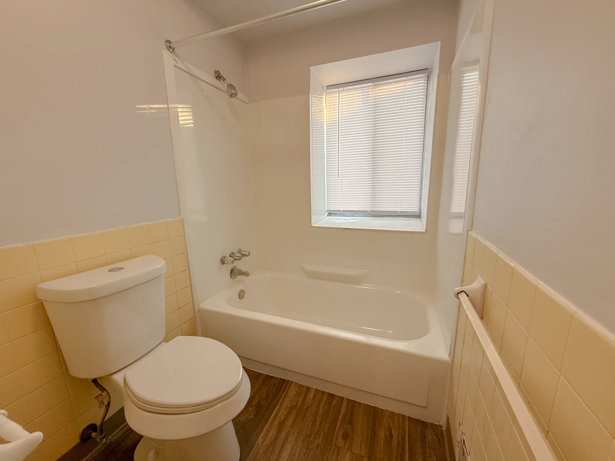 Inviting bathroom with natural wood floors, a classic bathtub, and soft lighting creating a cozy atmosphere.