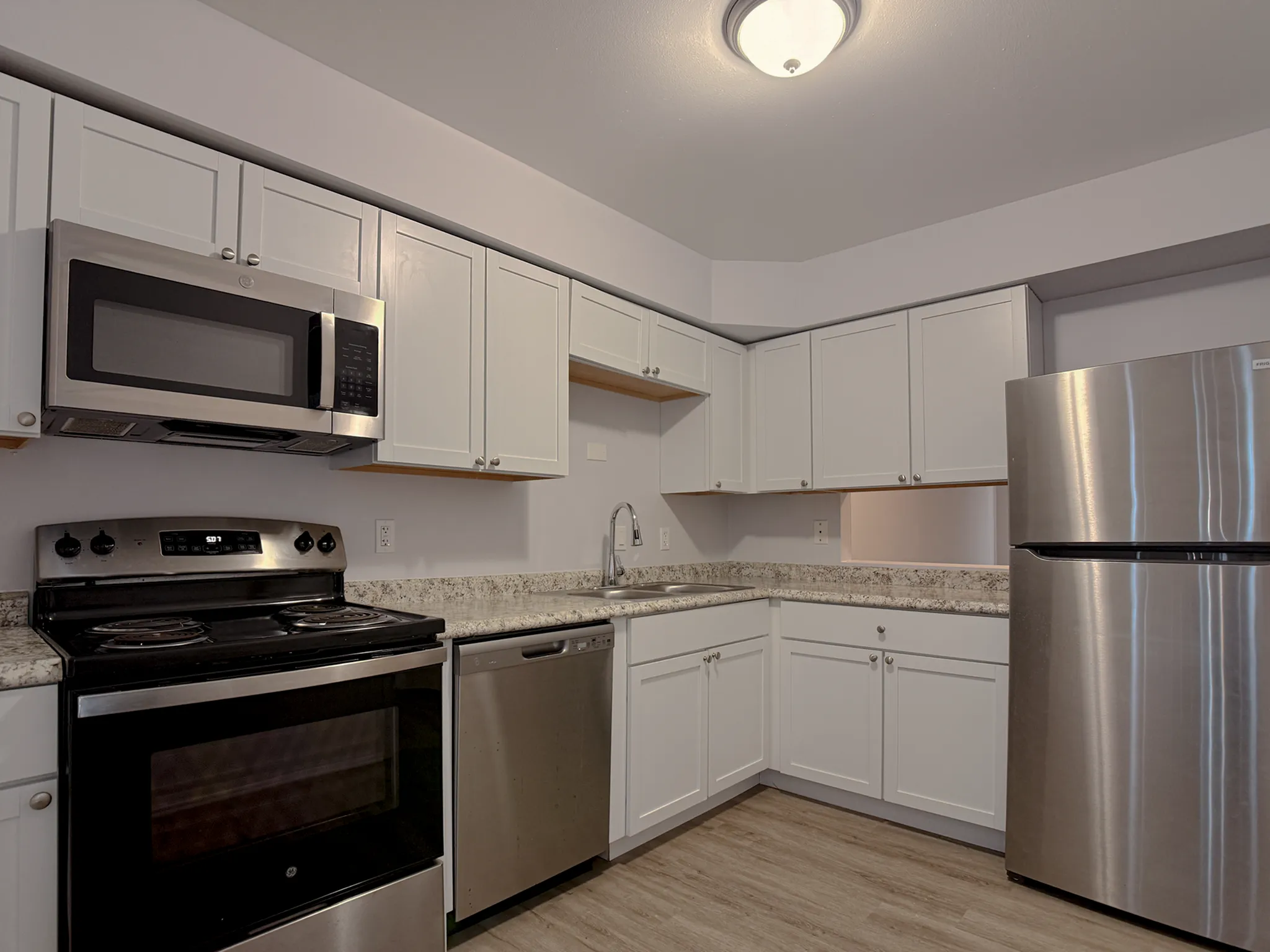 Modern kitchen with sleek stainless steel appliances, white cabinetry, and a polished granite countertop, offering a functional and stylish space.