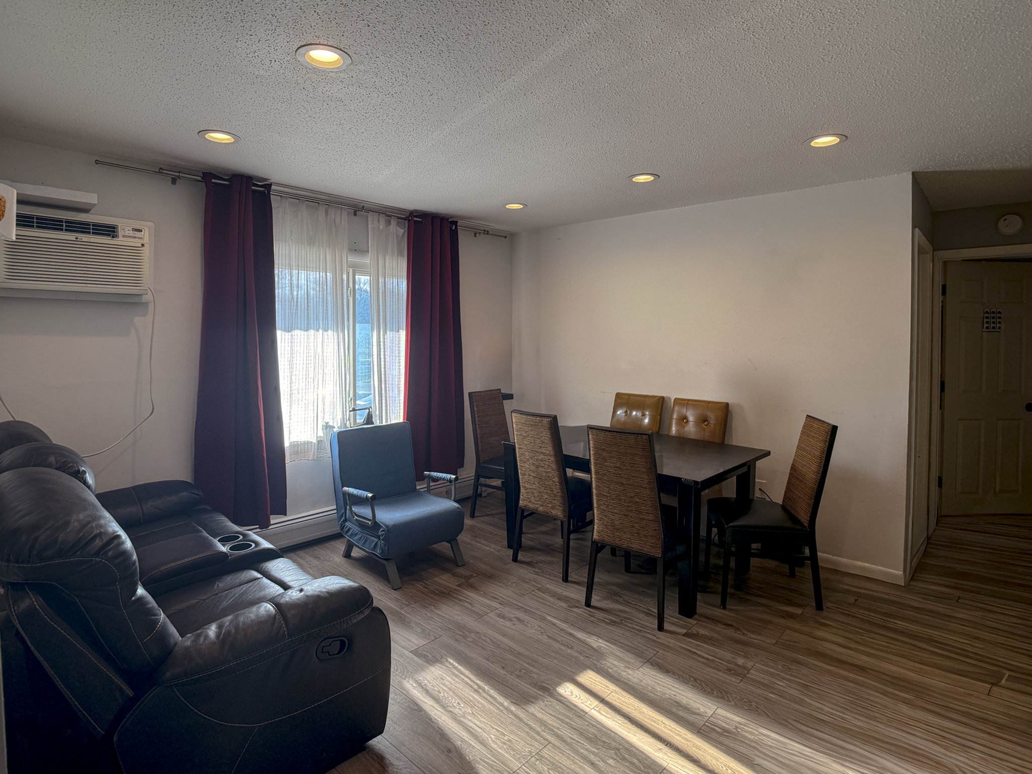 Inviting living and dining area with warm lighting, featuring a comfortable leather sofa, stylish dining table, and large window with elegant curtains.