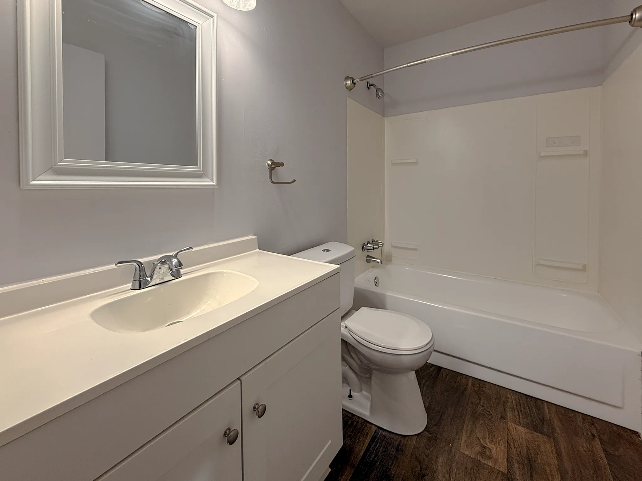 Modern bathroom with elegant fixtures, a spacious bathtub, and stylish vanity set against rich wood flooring.