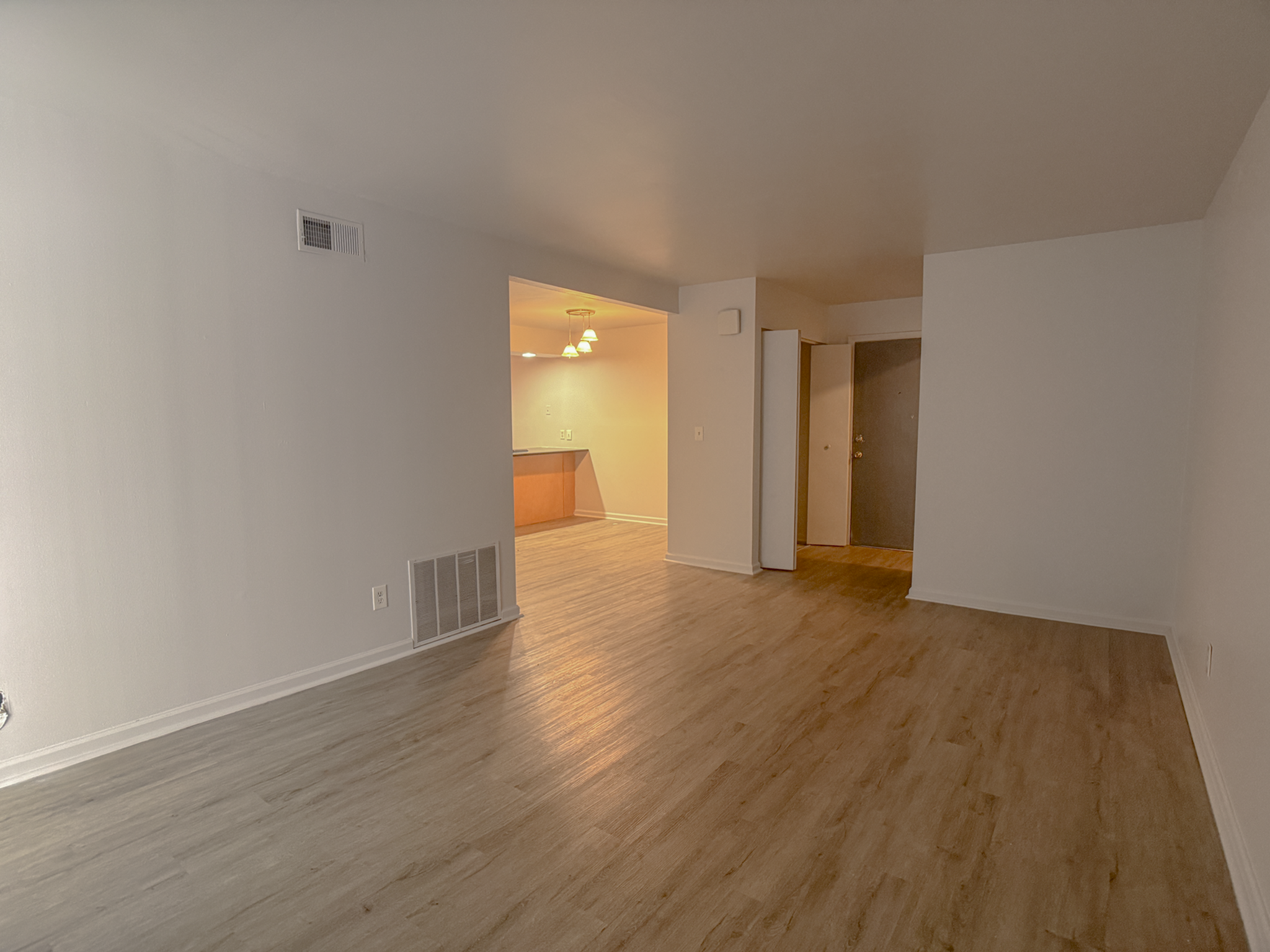 Spacious open-plan living area with warm wood flooring and a cozy dining nook.