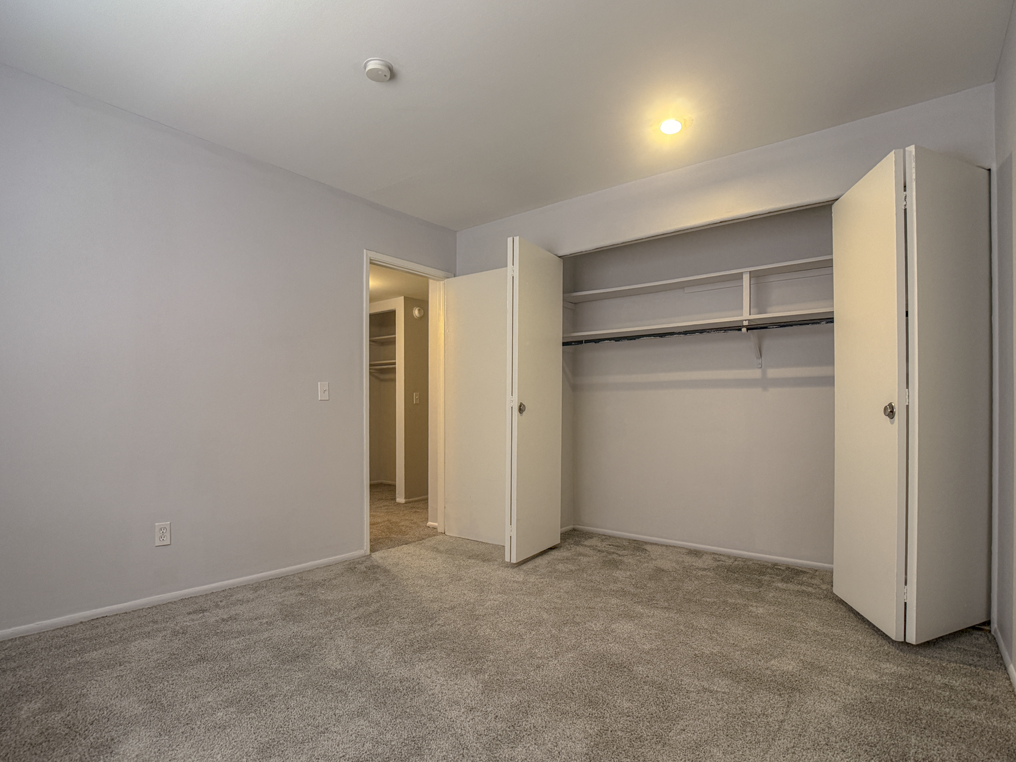 Bright, spacious bedroom featuring plush carpet, built-in closet, and soft lighting for a cozy atmosphere.