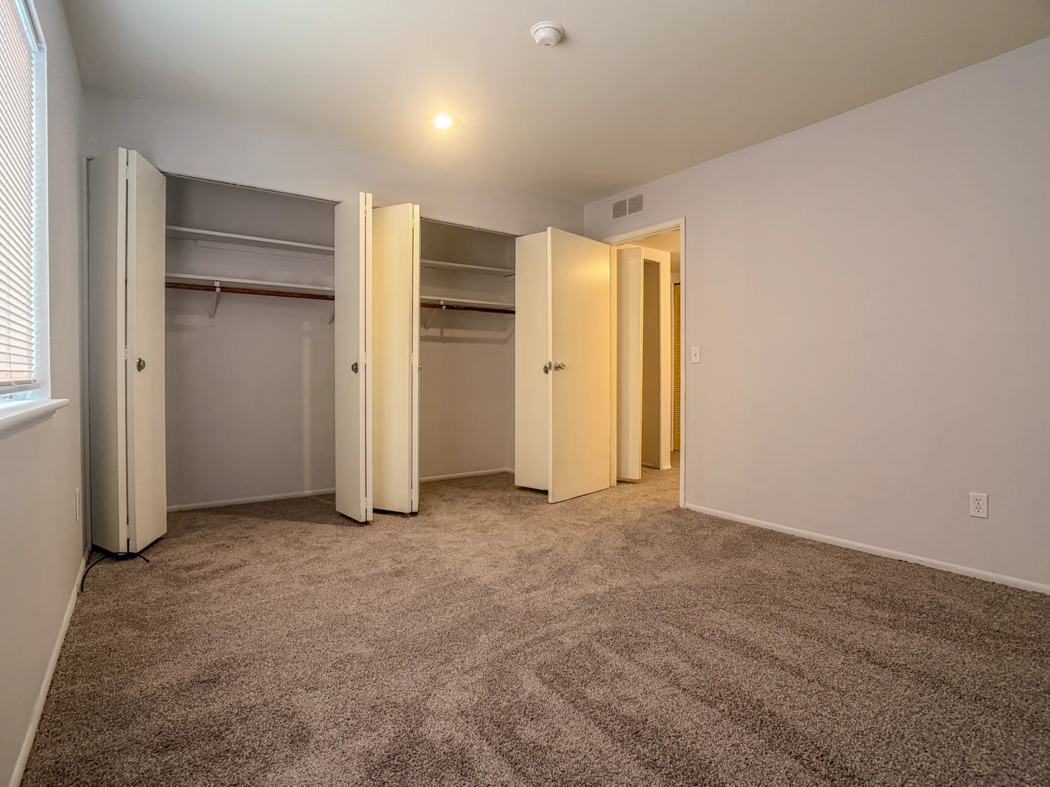 Spacious bedroom with plush carpet, ample closet space, and soft natural lighting.