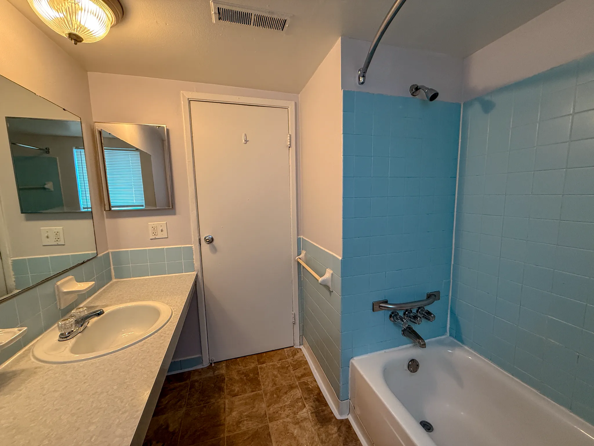 Bright, vintage bathroom with classic blue tiles, a spacious countertop with sink, and a relaxing bathtub.
