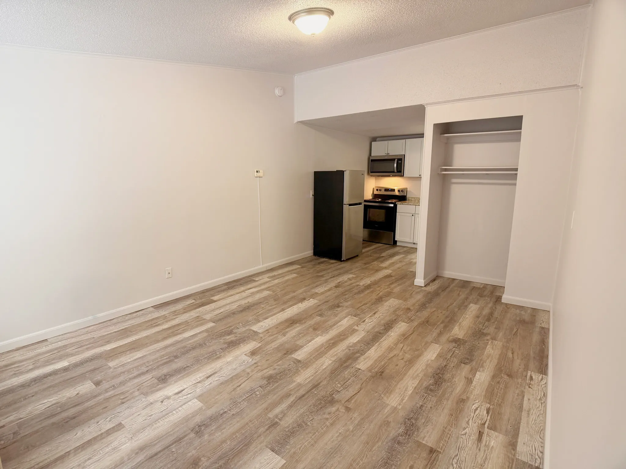 Modern apartment interior with stylish wooden flooring, sleek kitchen appliances, and open living space.