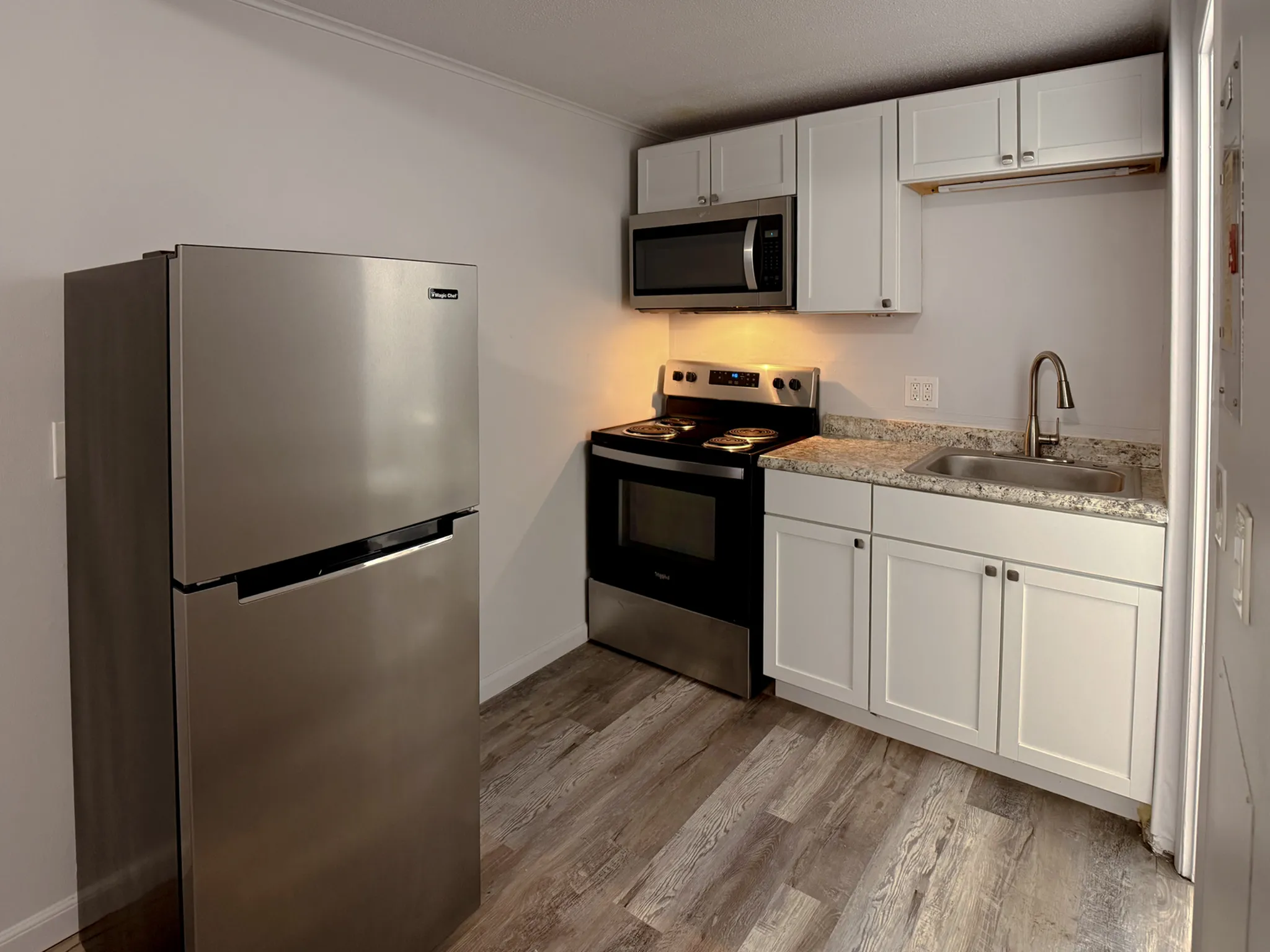 Modern kitchen featuring sleek stainless steel appliances, stylish white cabinetry, and elegant wood flooring.