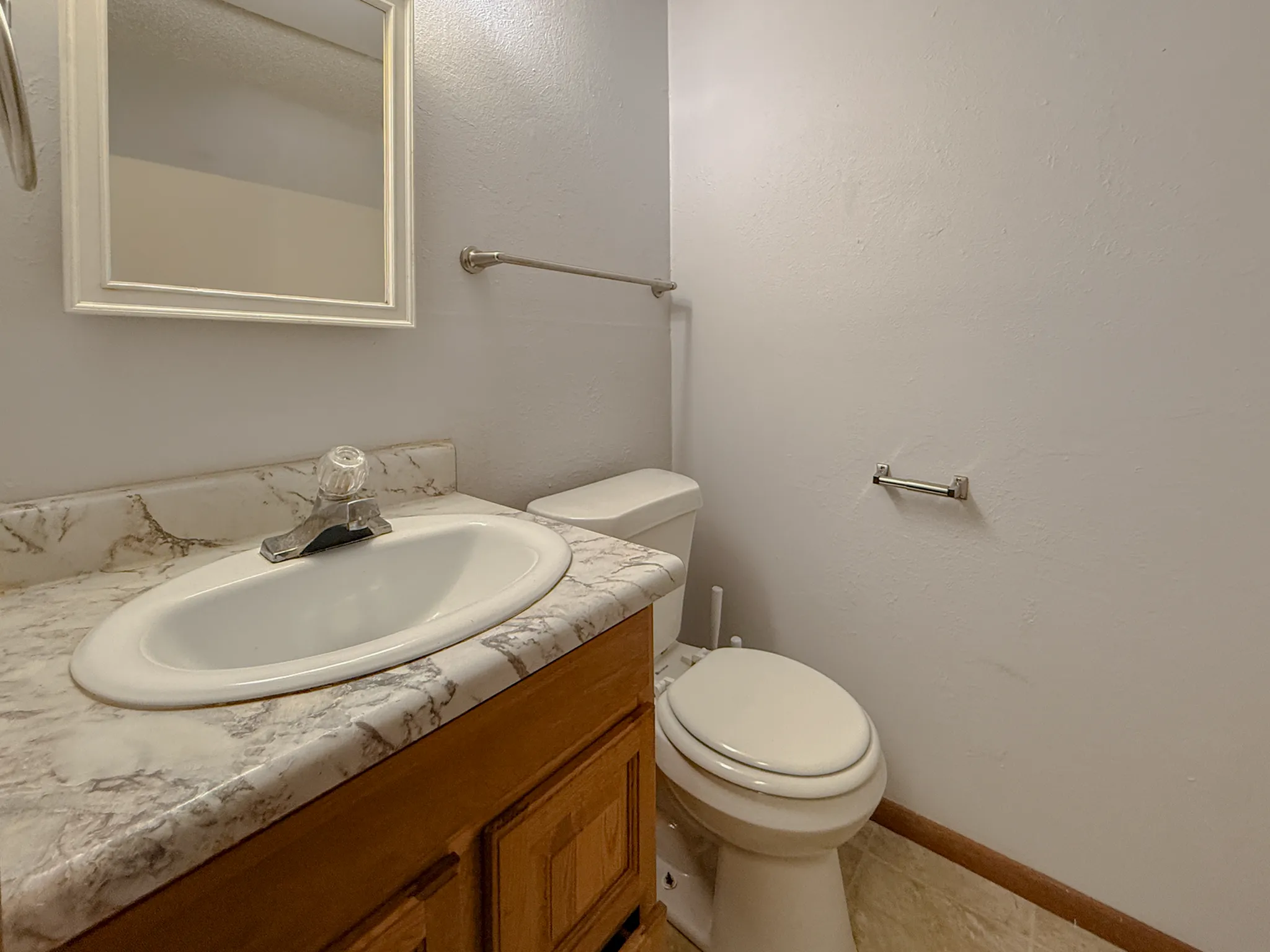 Modern bathroom with a marble countertop, elegant white sink, and stylish wooden cabinetry.