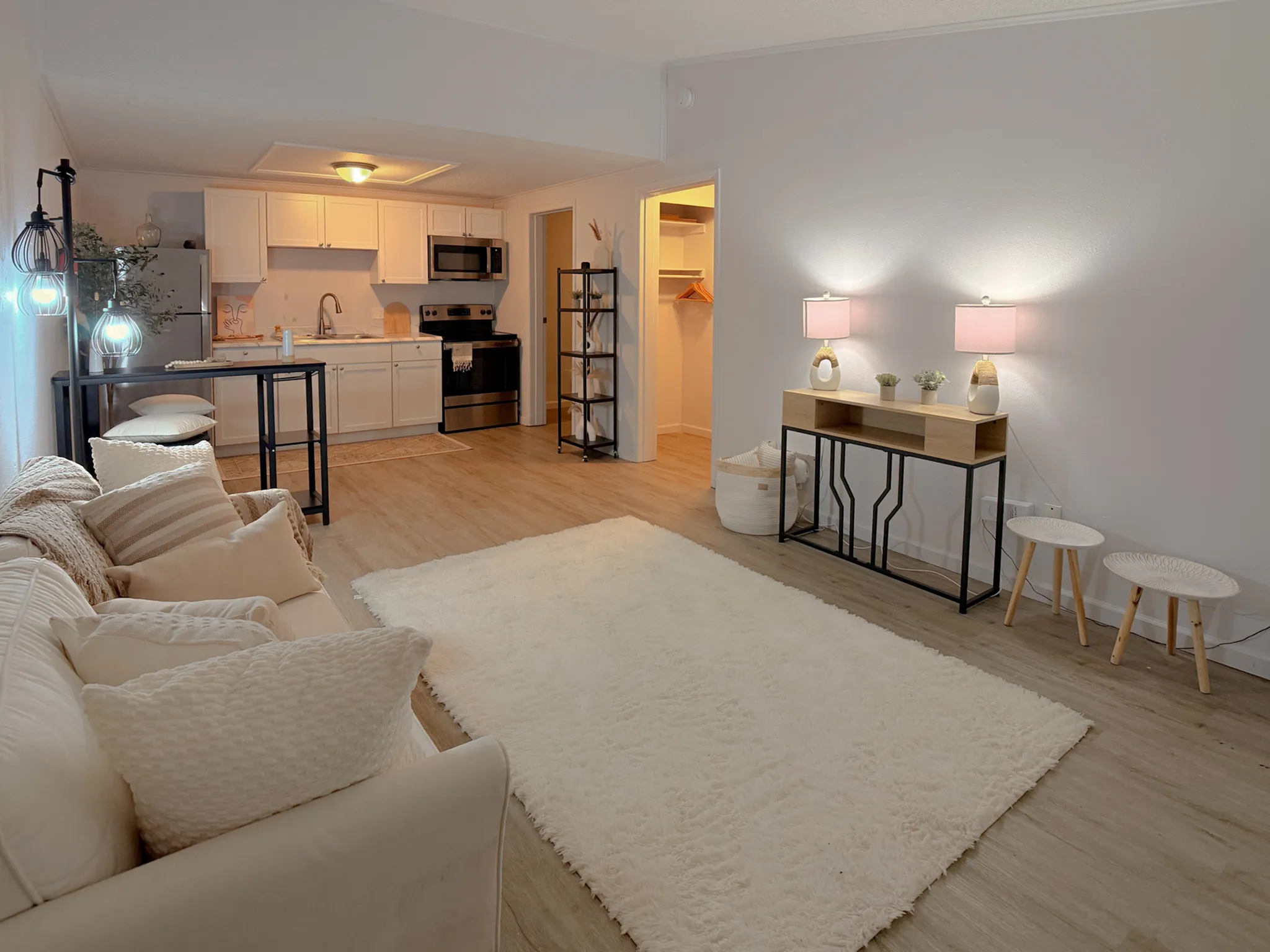 Charming open-concept living space with a cozy seating area, modern kitchen, and stylish decor, featuring soft lighting and warm tones.