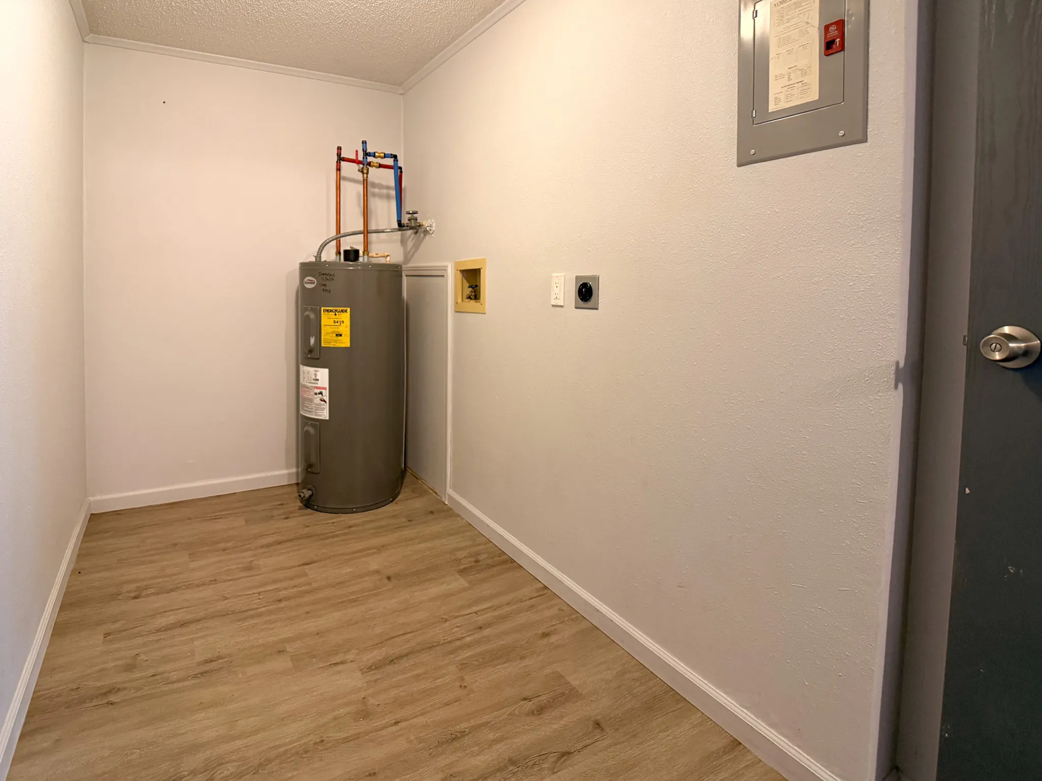 Cozy utility room with modern water heater and sleek laminate flooring, perfect for efficient home management.