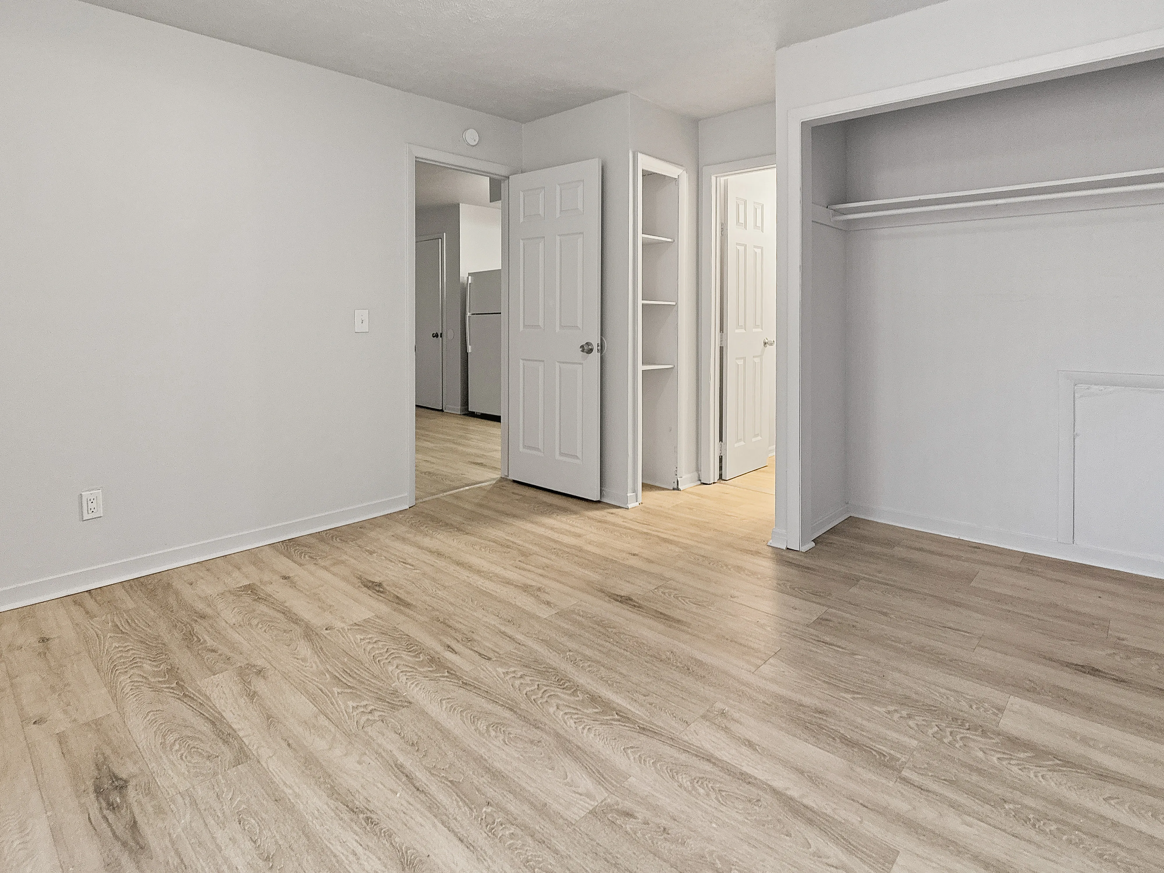 Inviting room with sleek wood flooring, open closet space, and modern white doors offering a bright, versatile living area.