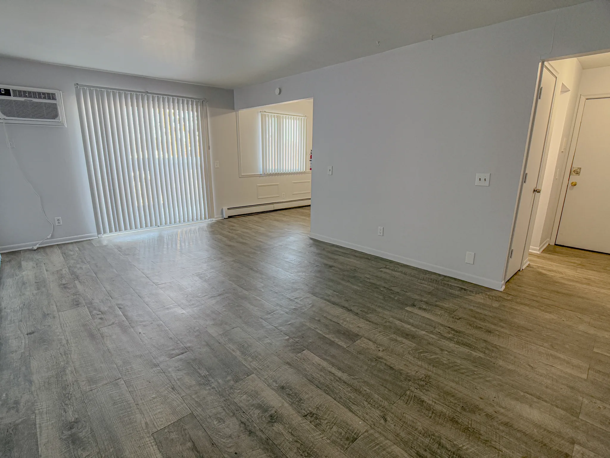 Bright and spacious living area with modern wood flooring and large sliding glass doors, perfect for natural light.