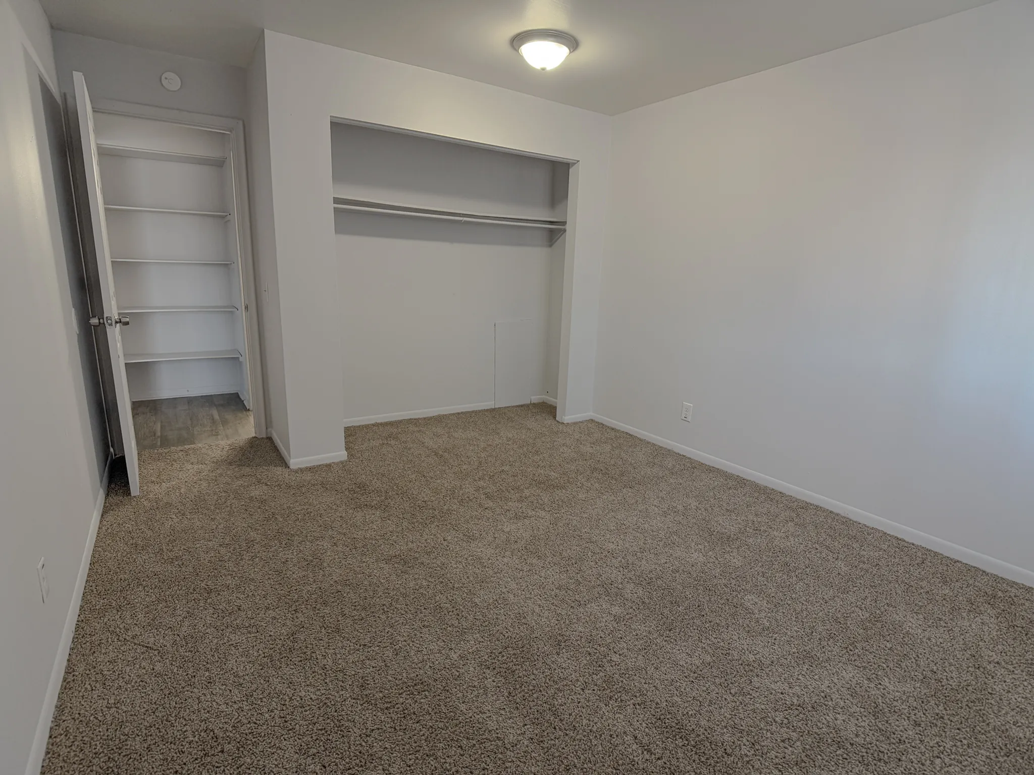 Bright, spacious bedroom with plush carpeting, built-in shelving, and ample closet space.