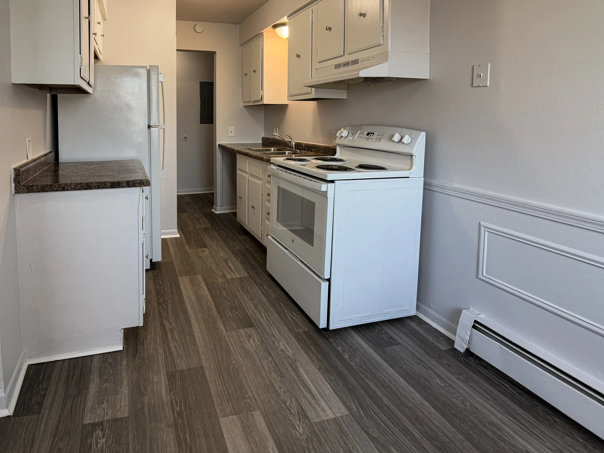 Modern kitchen featuring sleek white cabinets, spacious countertops, and elegant wood flooring.