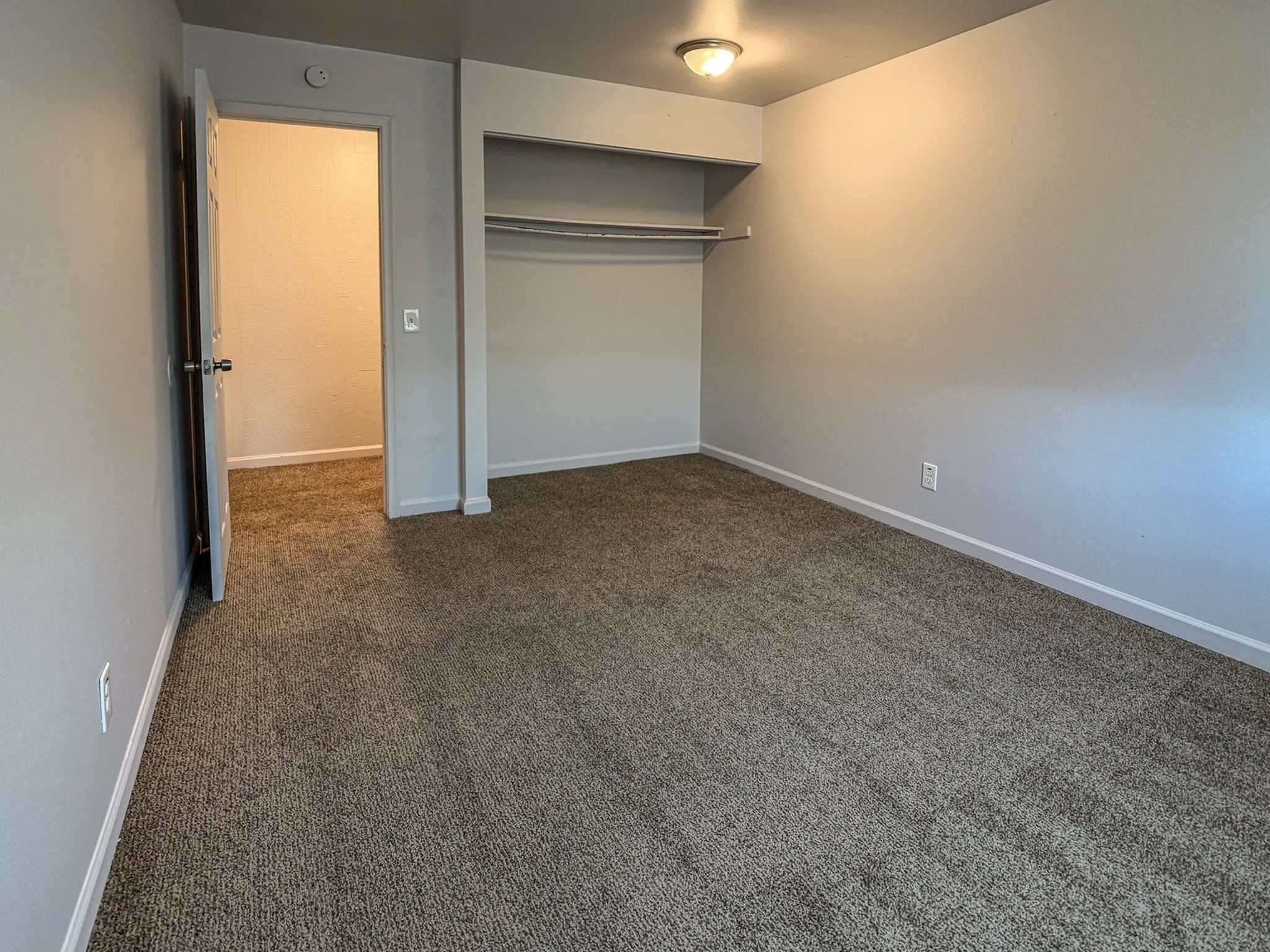 Spacious bedroom with plush carpeting, soft lighting, and ample closet space offering comfort and style.