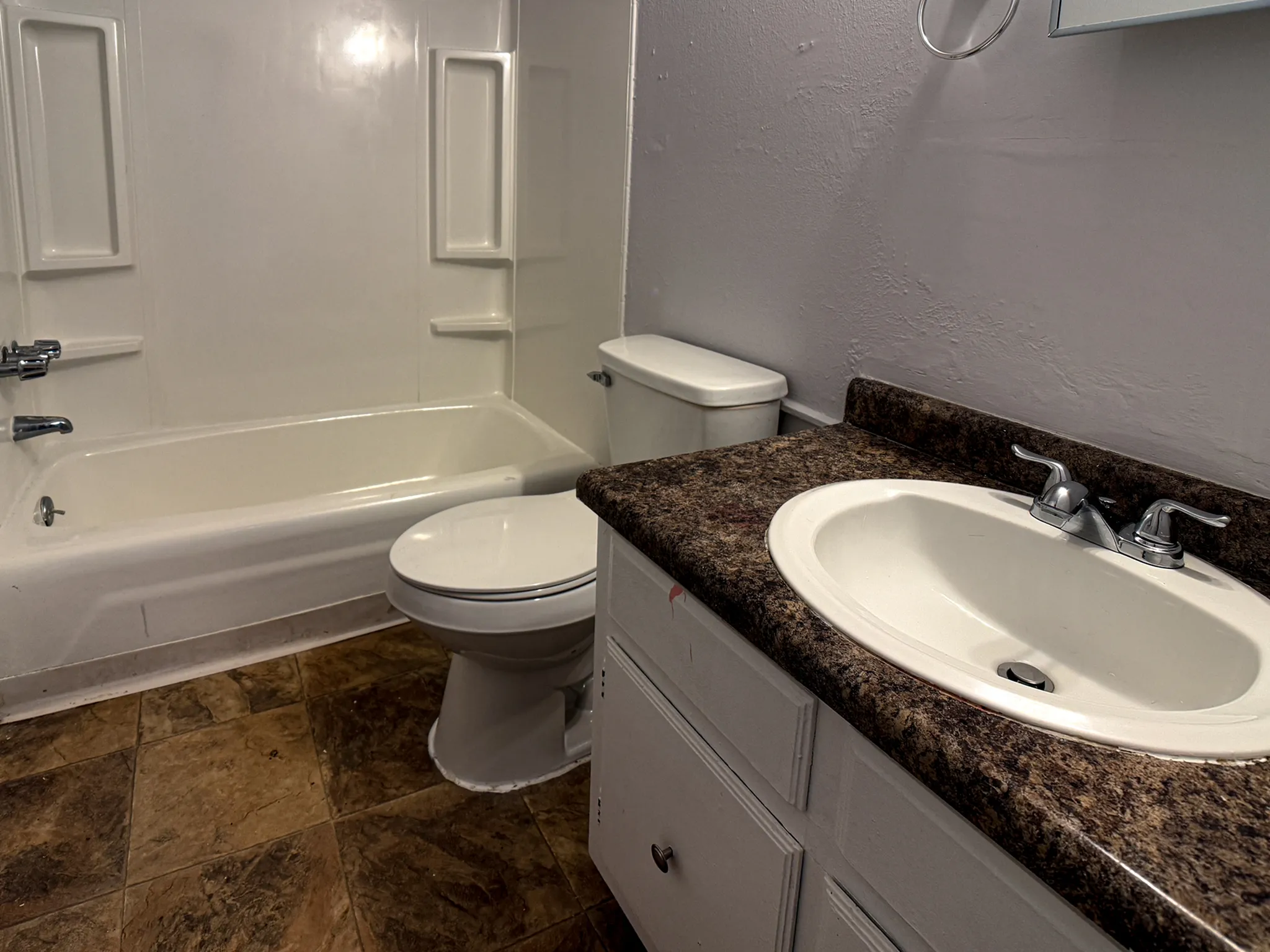 Modern bathroom with elegant brown countertop, sleek white sink, and pristine bathtub, offering a serene space for relaxation.