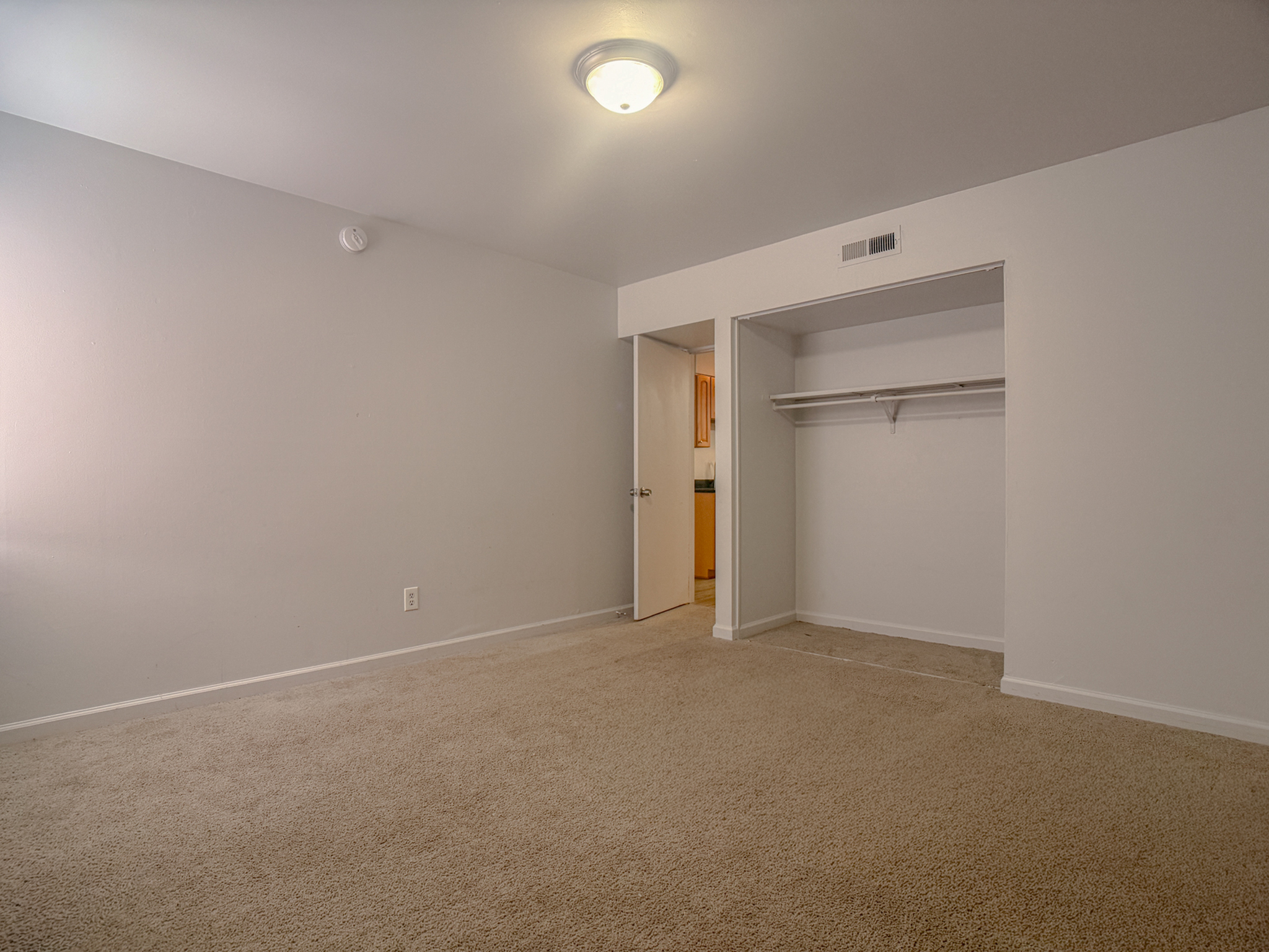 Inviting bedroom with plush carpeting and spacious walk-in closet, offering cozy and practical living space.