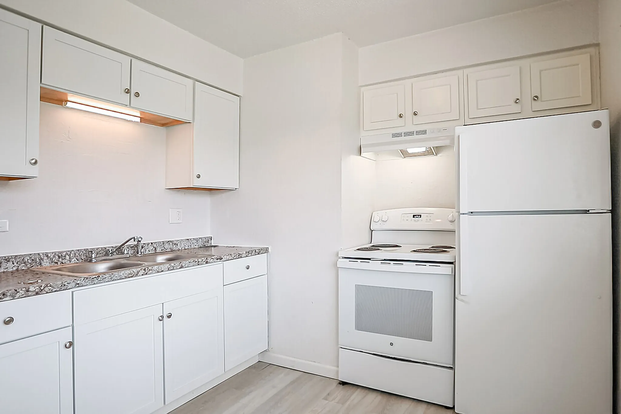 Bright, modern kitchen with sleek white cabinetry and granite countertops, featuring a spacious fridge and electric stove.