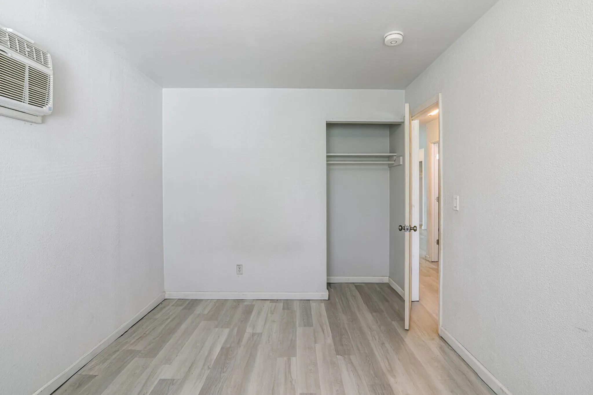 Bright and spacious bedroom with elegant flooring and ample closet space, perfect for a serene living environment.