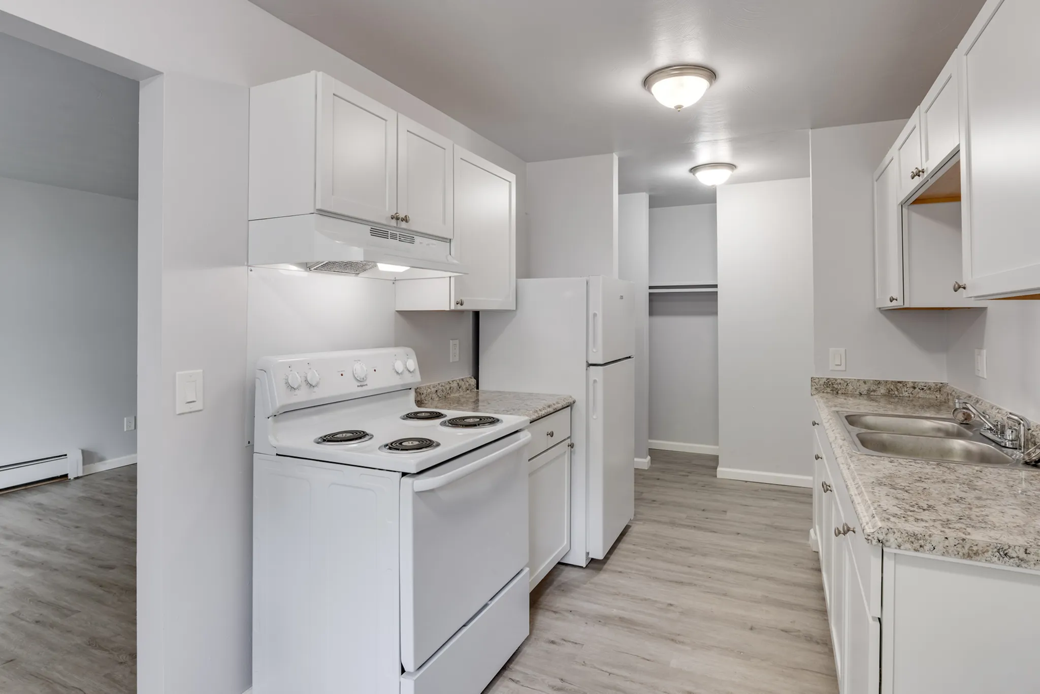 Modern kitchen with sleek white cabinetry, electric stove, and spacious countertops in a welcoming apartment layout.